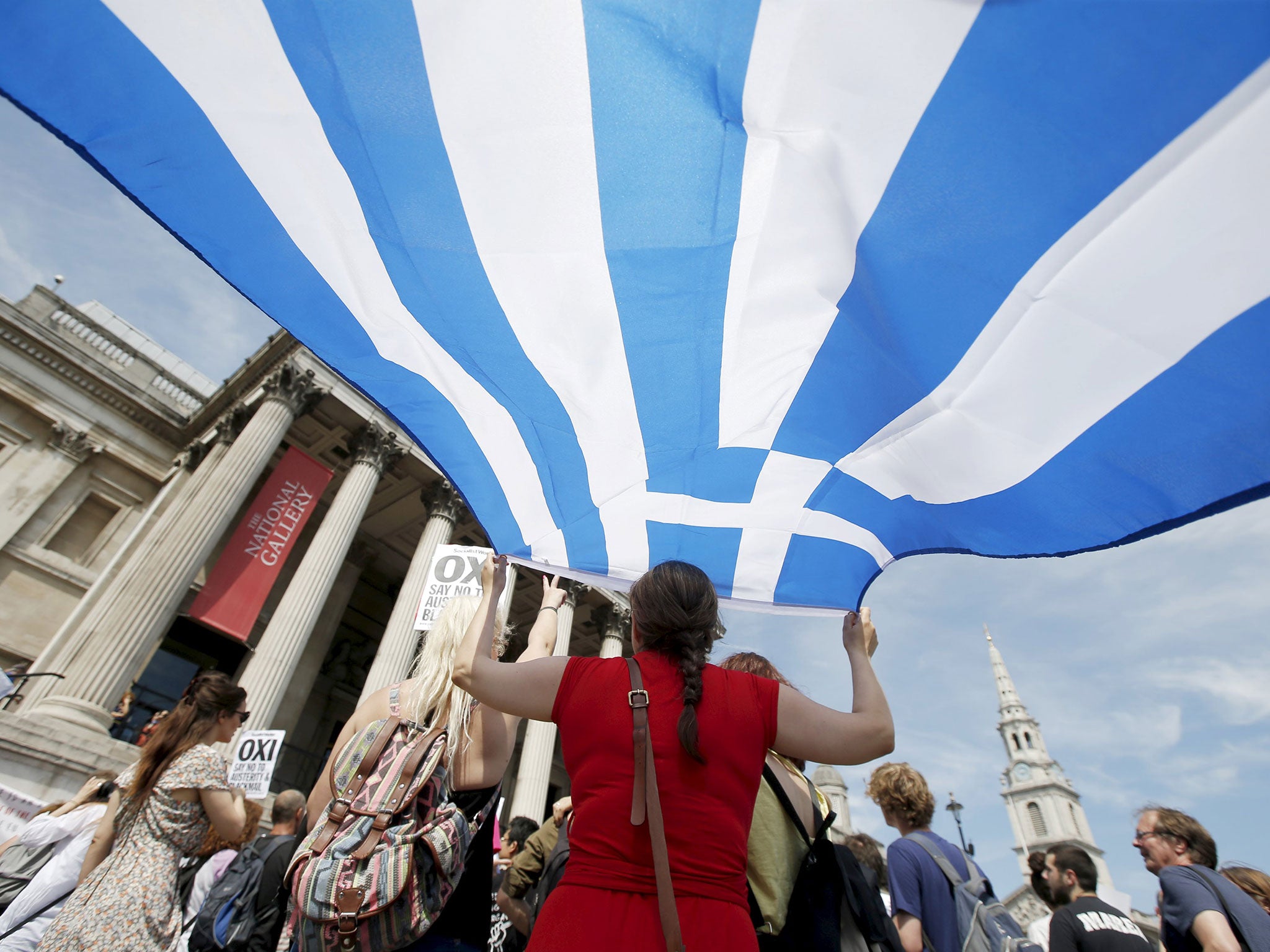 A woman holds the flag of Greece at the 'Greek solidarity festival' in Trafalgar Square, London. The event was held in support of the people of Greece and the cancellation of debt, ahead of their referendum