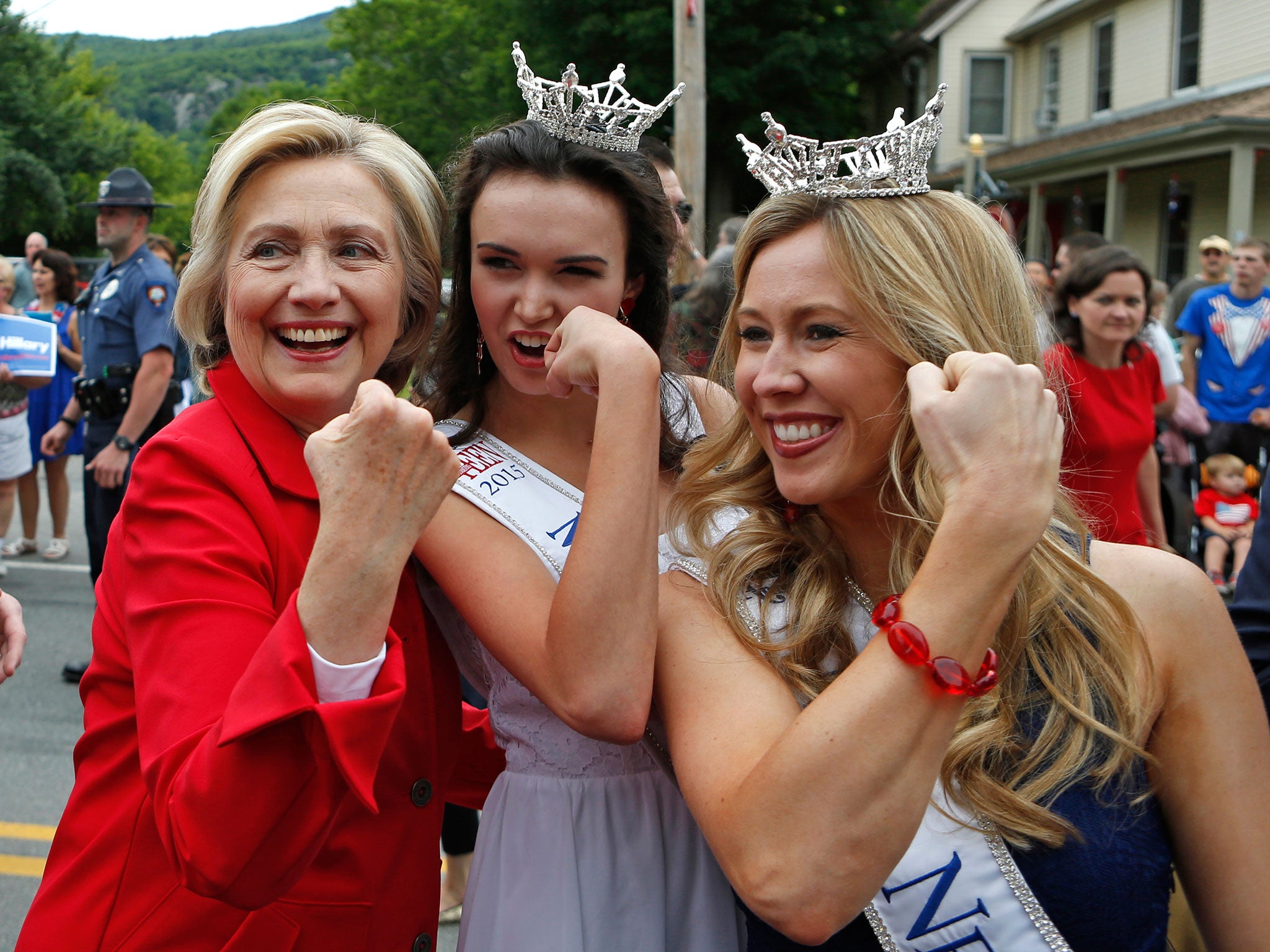 Democratic presidential candidate Hillary Rodham Clinton flexes her muscles with Miss Teen New Hampshire Allie Knault, center, and Miss New Hampshire Holly Blanchard, during a Fourth of July parade in Gorham, USA