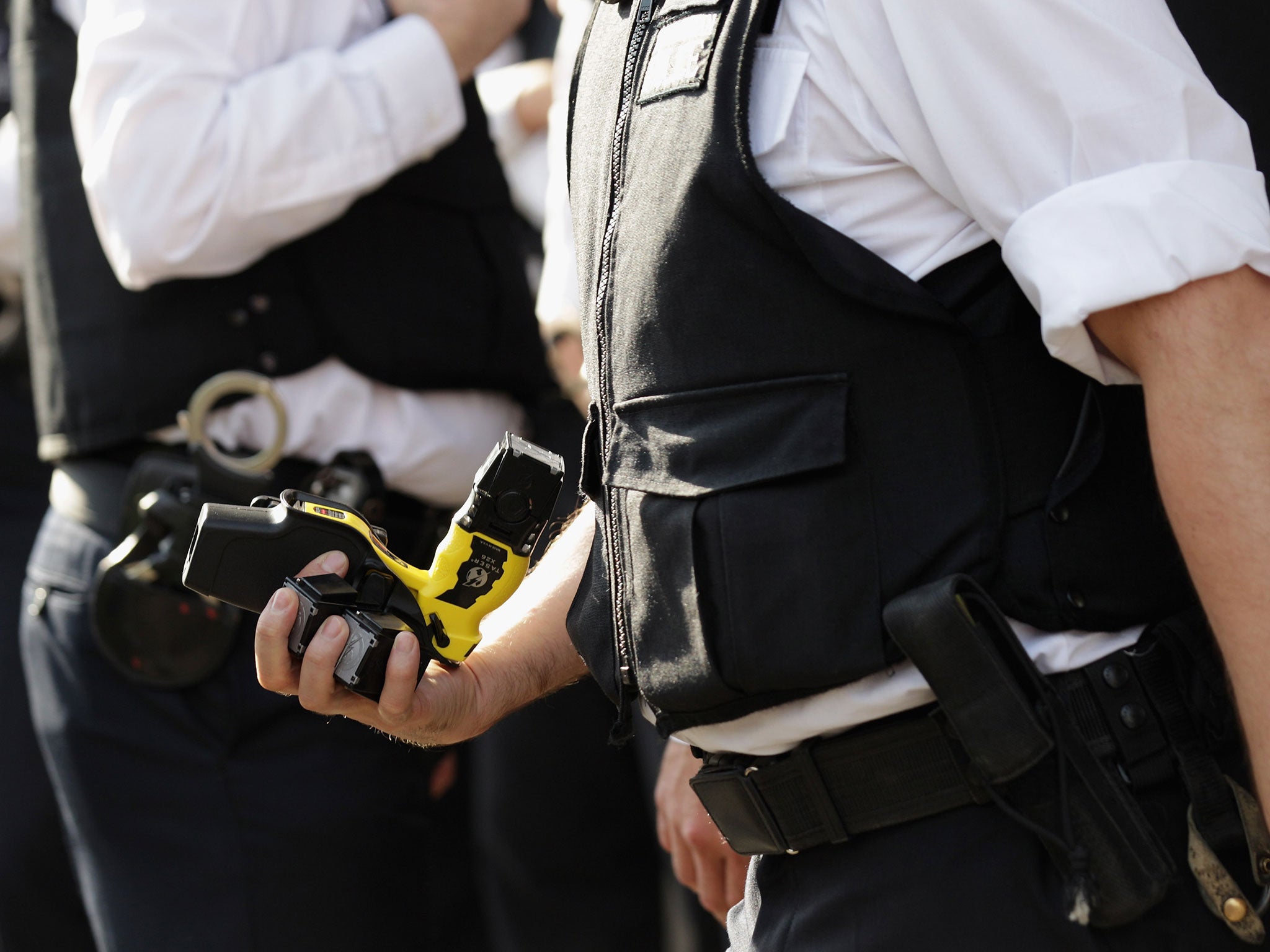 A police officer removes a TASER weapon from a colleague (Getty)