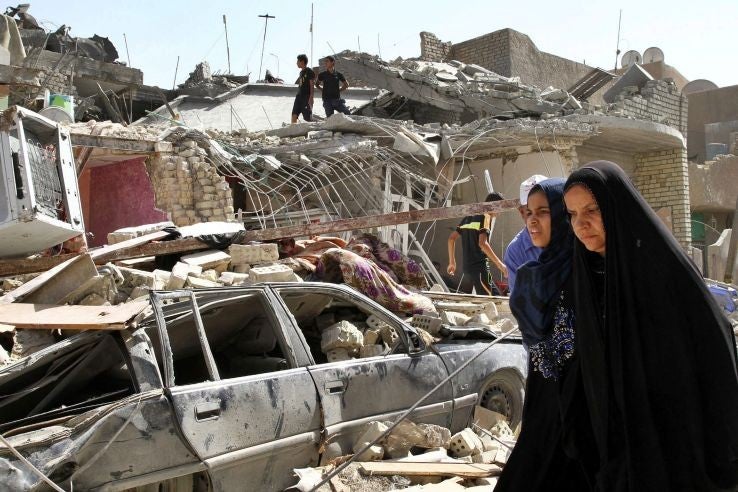 Women walk past the rubble of a house destroyed in the accidental bombing