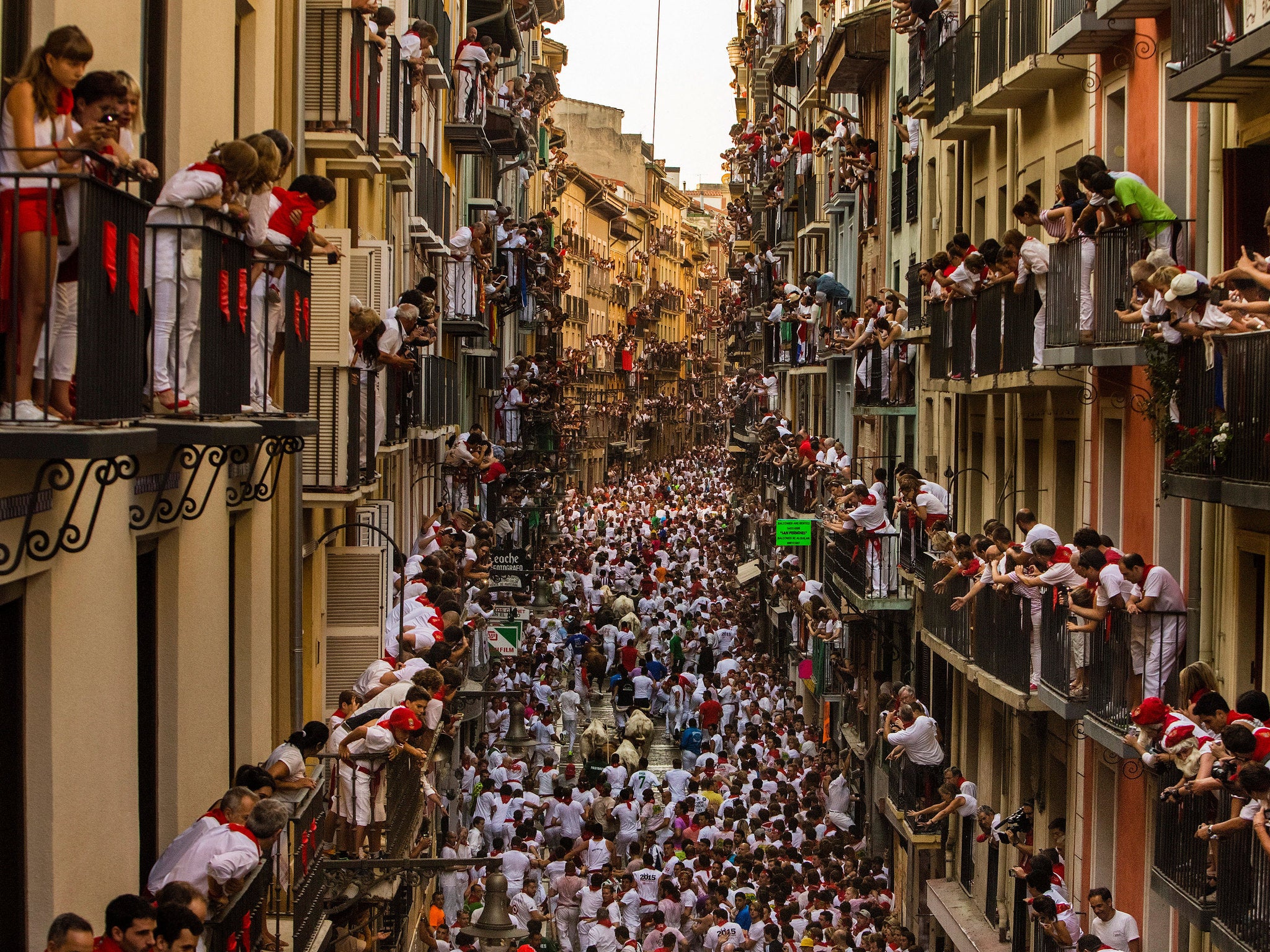 People watch as Jandilla fighting bulls and revelers run during the running of the bulls at the San Fermin festival in Pamplona, Spain