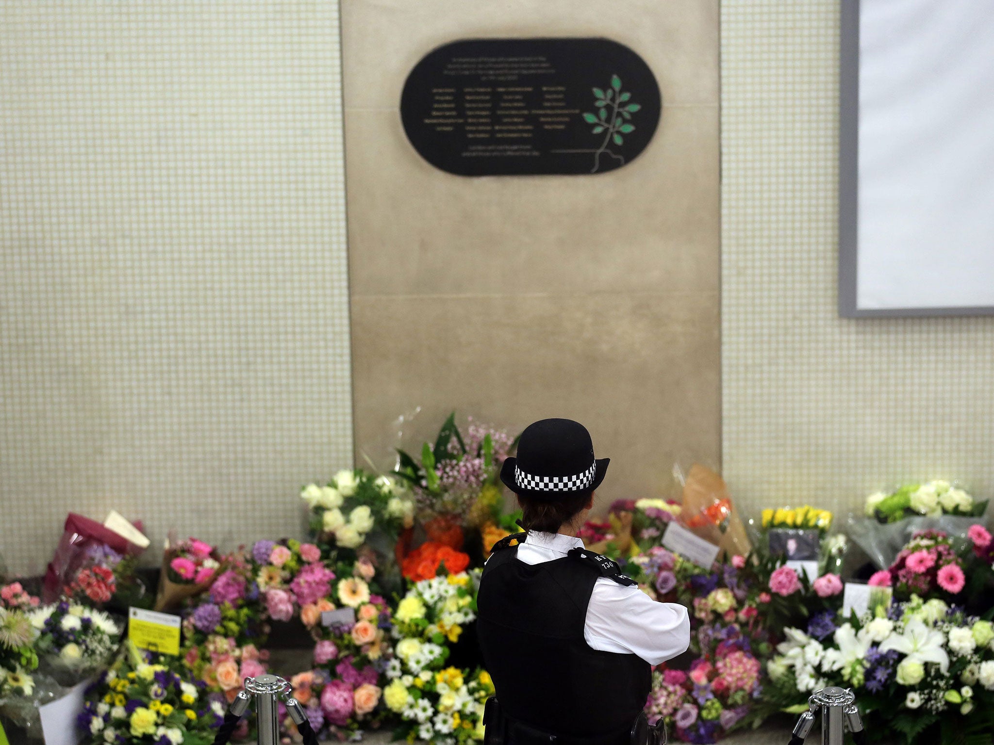 A police officer looks at flowers left at Kings Cross Underground station in London