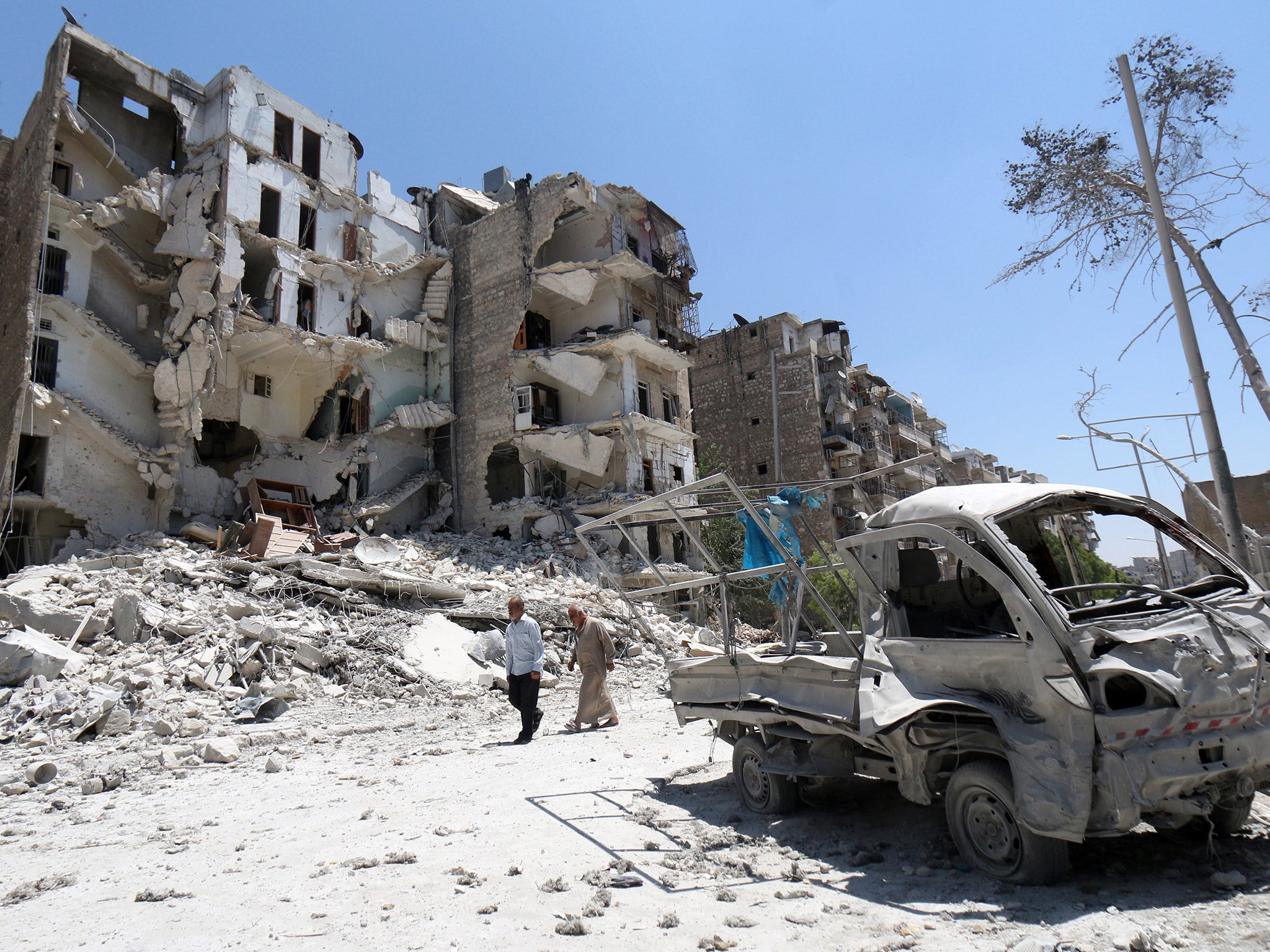Syrian men walk amidst the rubble and debris in the Qadi Askar district of the northern city of Aleppo (Getty)