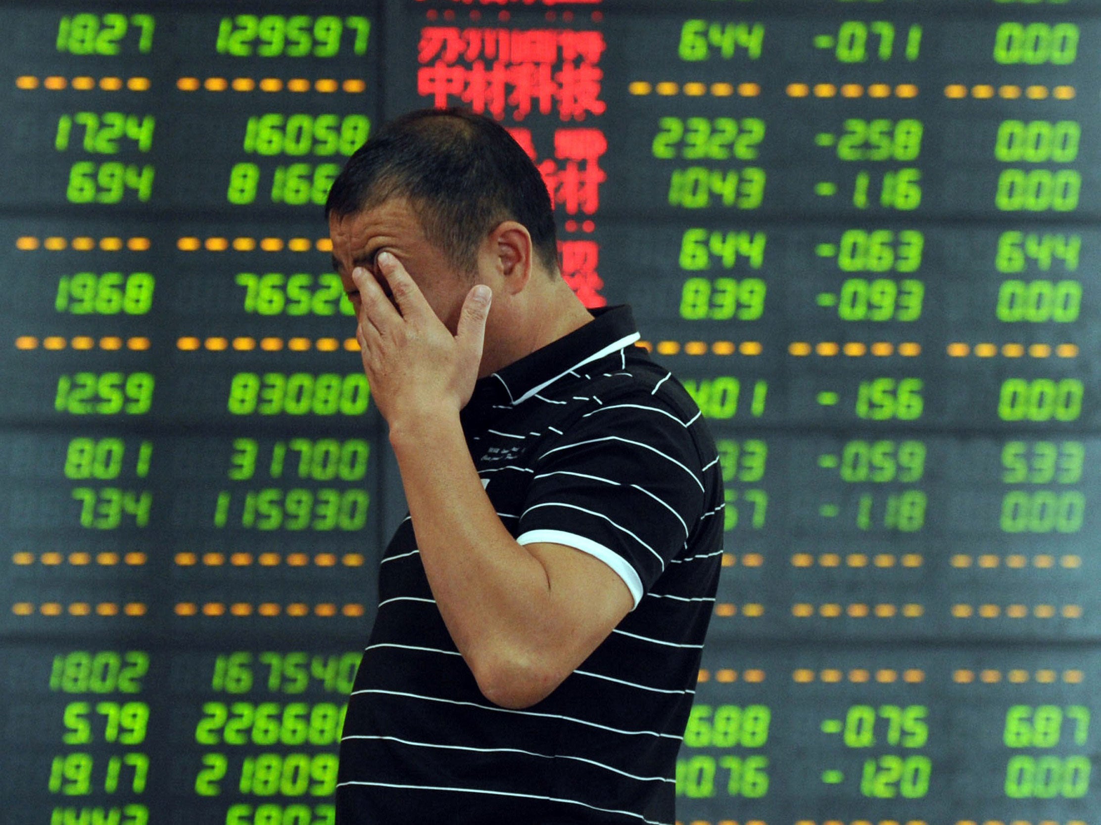 An investor reacts in front of a screen showing stock market movements in Fuyang, eastern China's Anhui province.