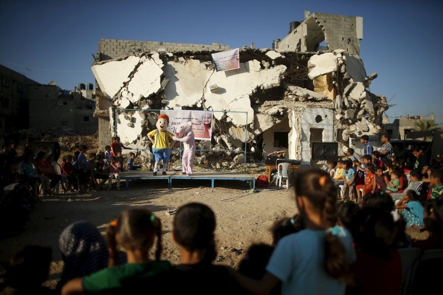 Children watch a performance in the ruins of a house destroyed by Israeli shelling during Operation Protective Edge