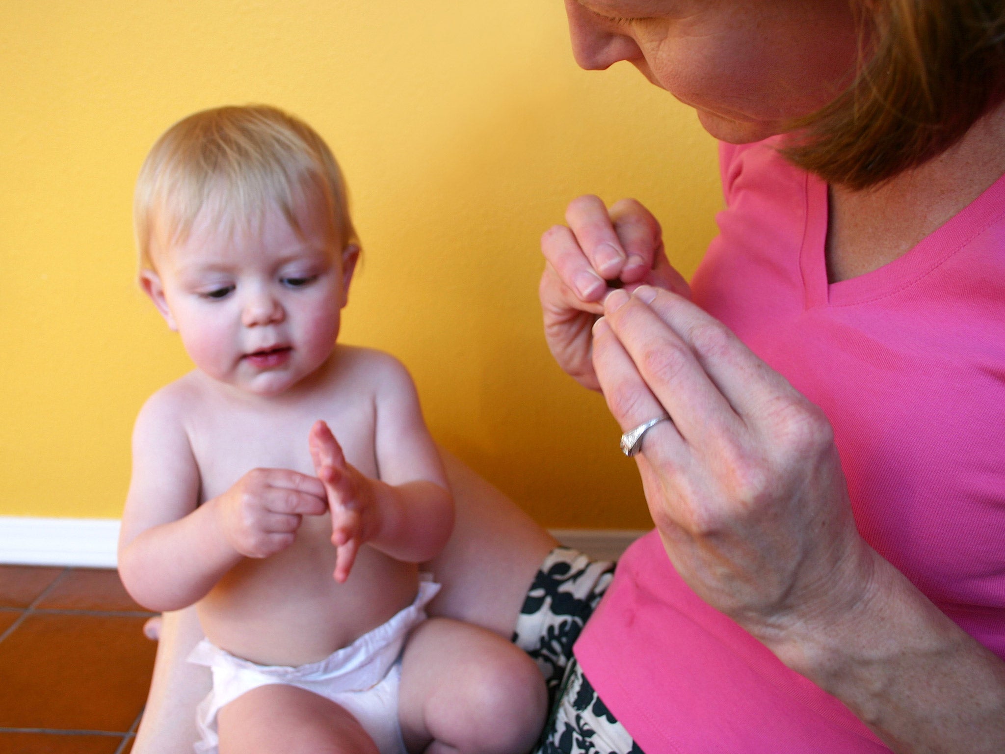 A mother communicating with her infant daughter using sign language. File photo