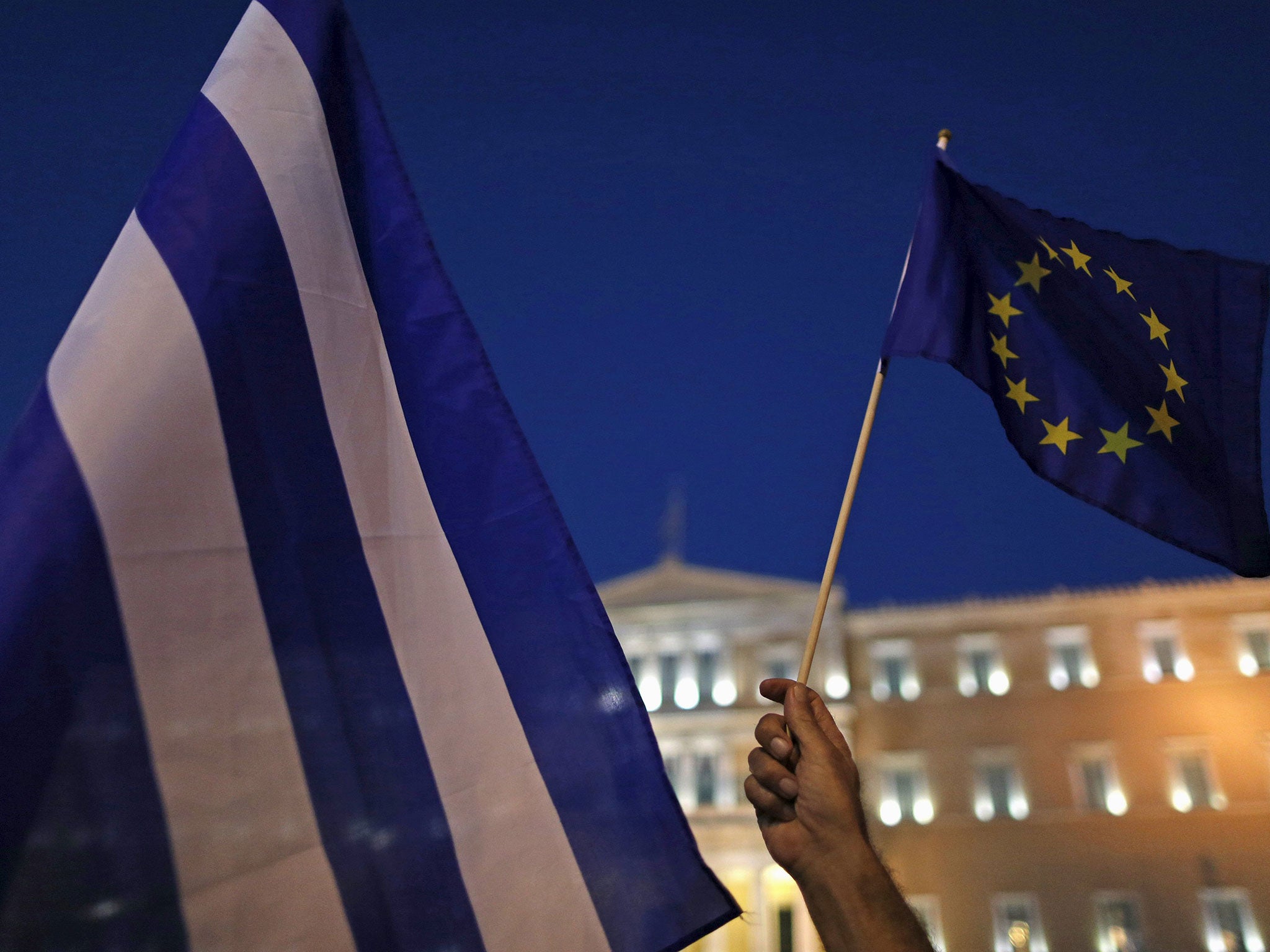 Protesters hold European Union and Greek flags during a Pro-Euro rally in front of the parliament building in Athens
