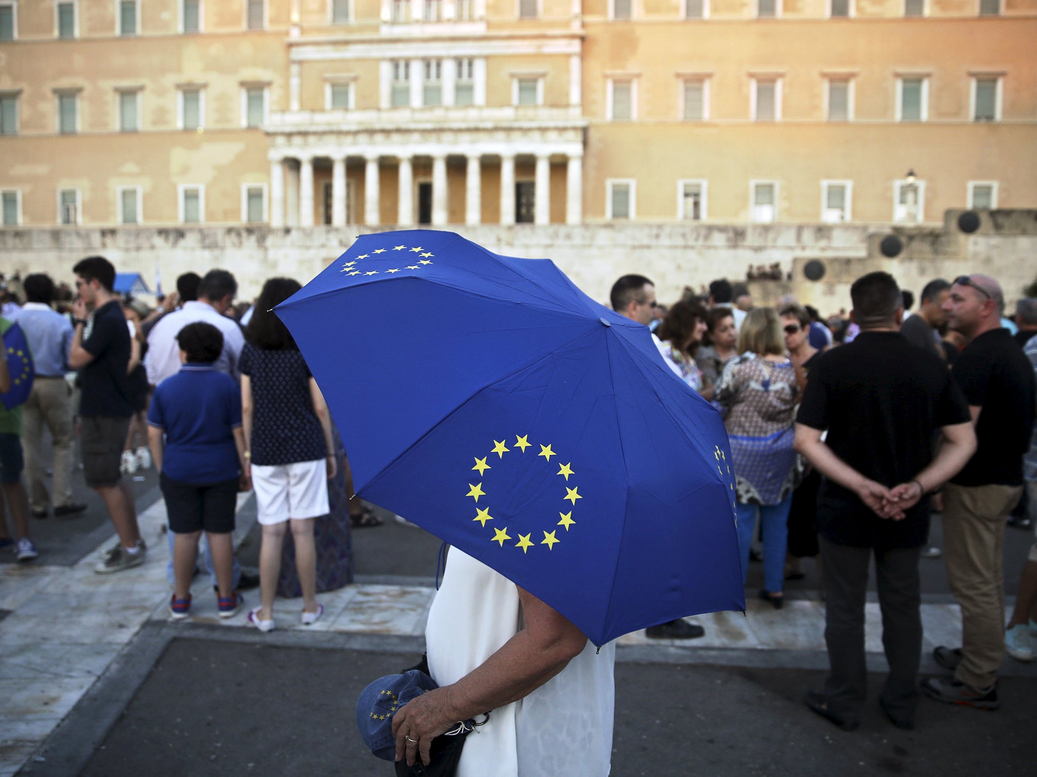 A pro-Euro protester holds an umbrella with the European Union symbol during a rally in front of the parliament building in Athens