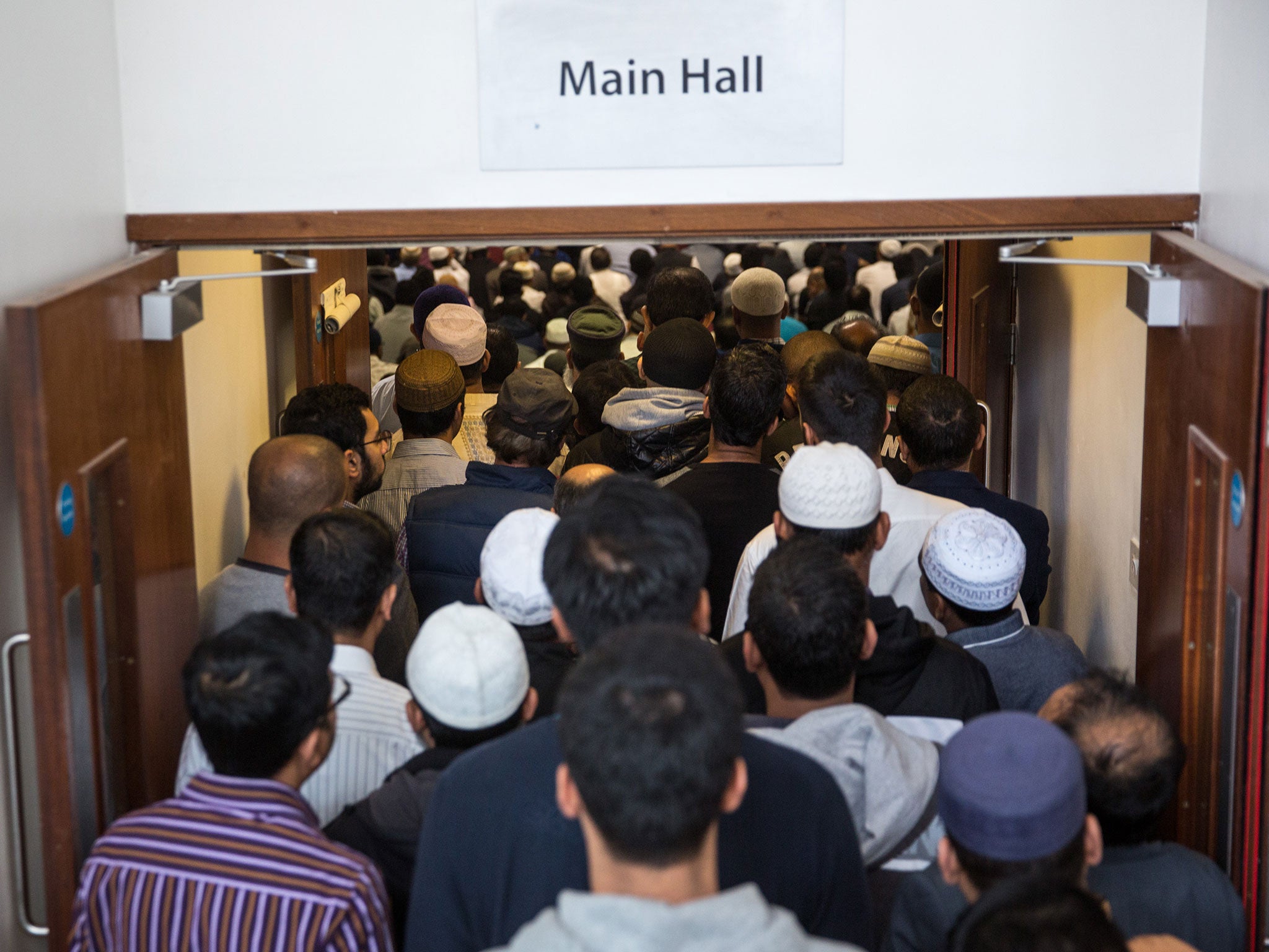 Men queue to enter the main prayer hall of the East London Mosque for the first Friday prayers of the Islamic holy month of Ramadan