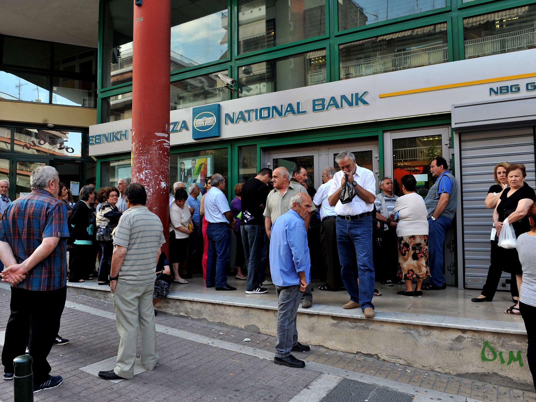 Pensioners stand outside a closed branch of the Greek National bank in Thessaloniki on June 29, 2015