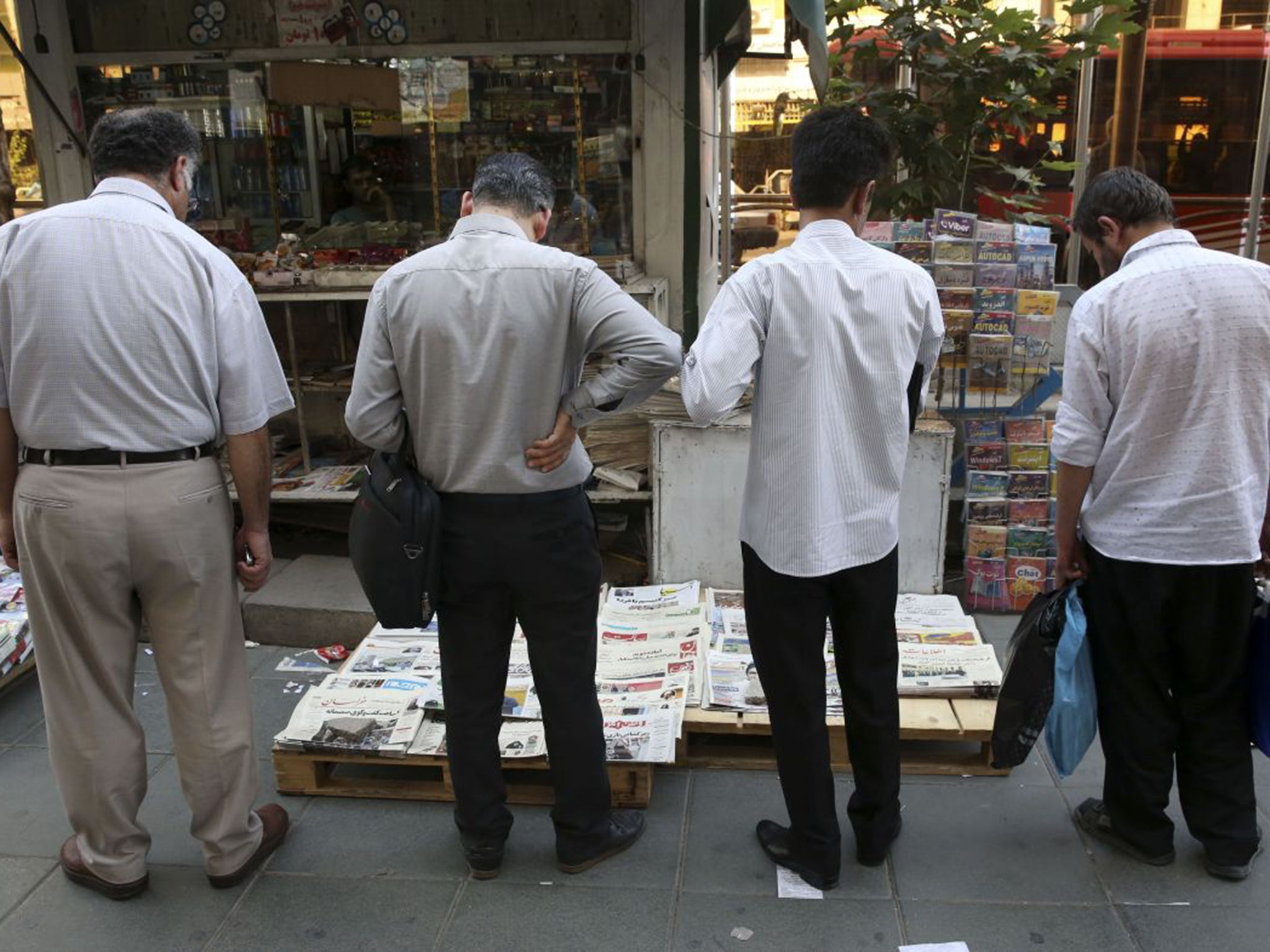 Iranian men scan newspapers in downtown Tehran, Iran, as the talks continued