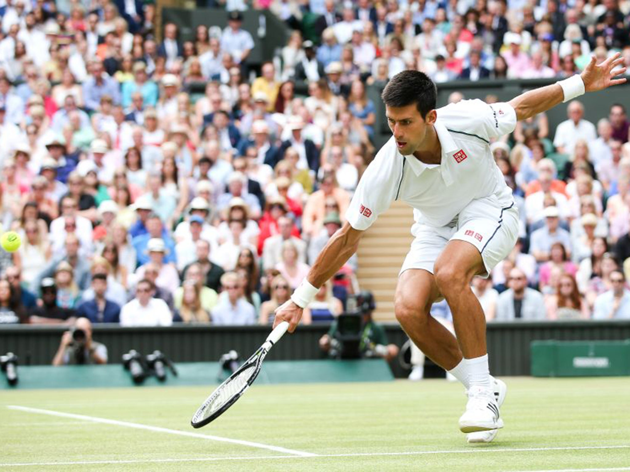 Novak Djokovic reaches low to make a return against Roger Federer