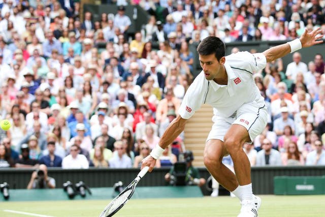 Novak Djokovic reaches low to make a return against Roger Federer 