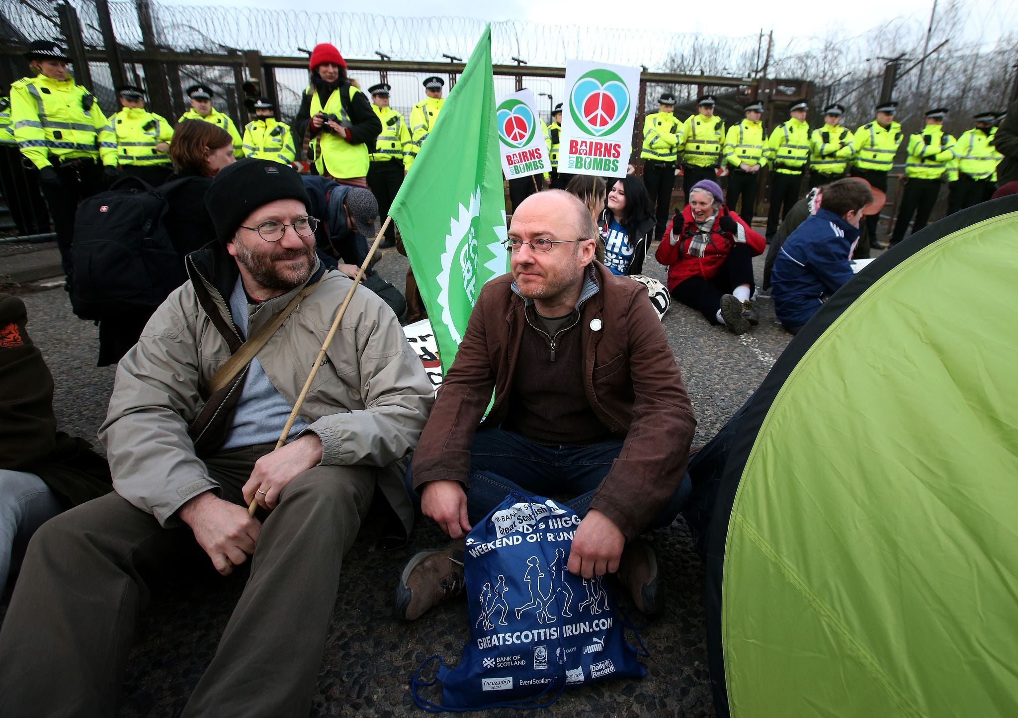 Scottish Green Party leader Patrick Harvie (right) joins anti-Trident demonstrators sitting on the road at the North entrance at HM Naval Base Clyde, Faslane.