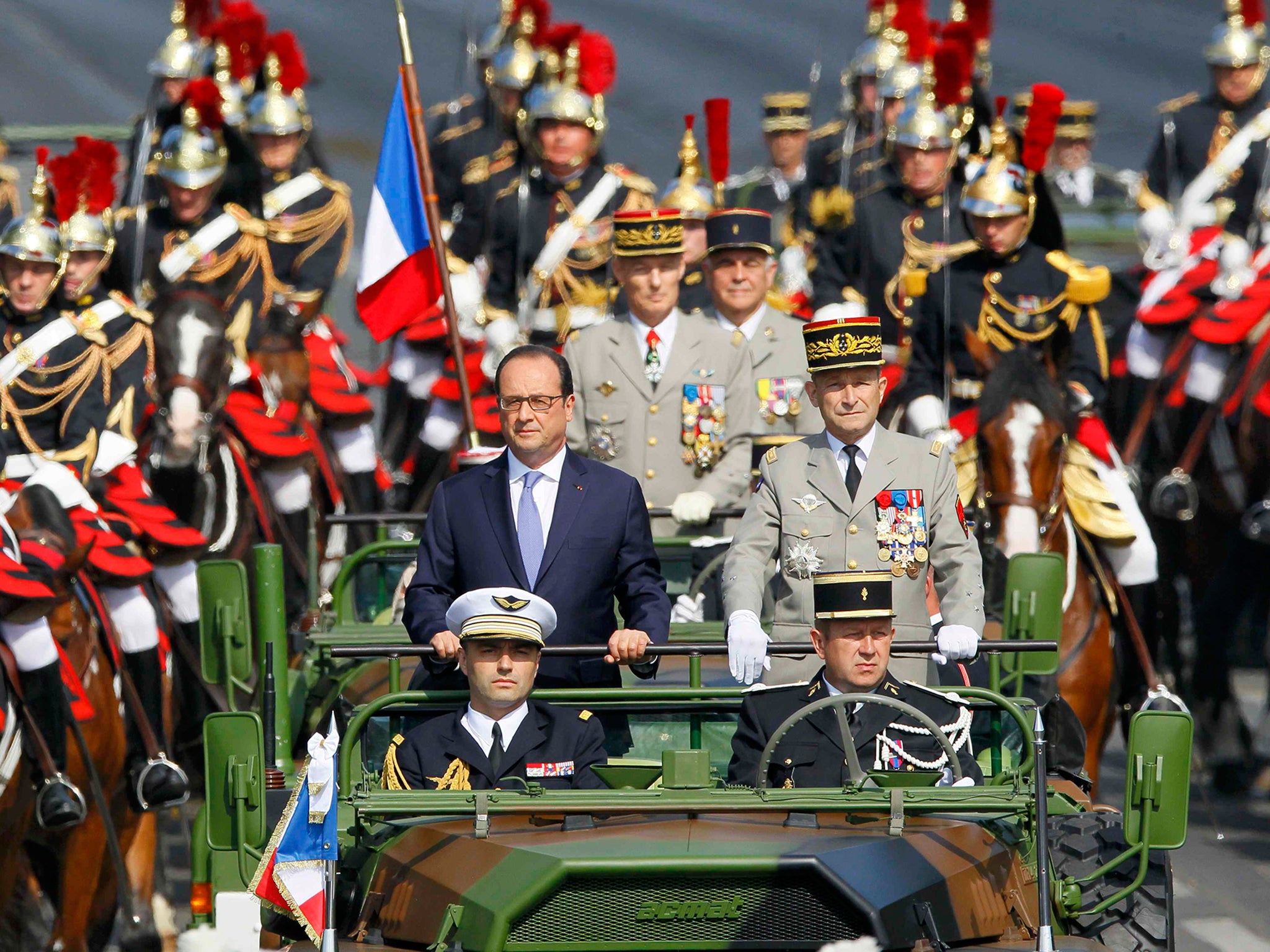 French President Francois Hollande reviews the troops while descending from the Champs Elysees