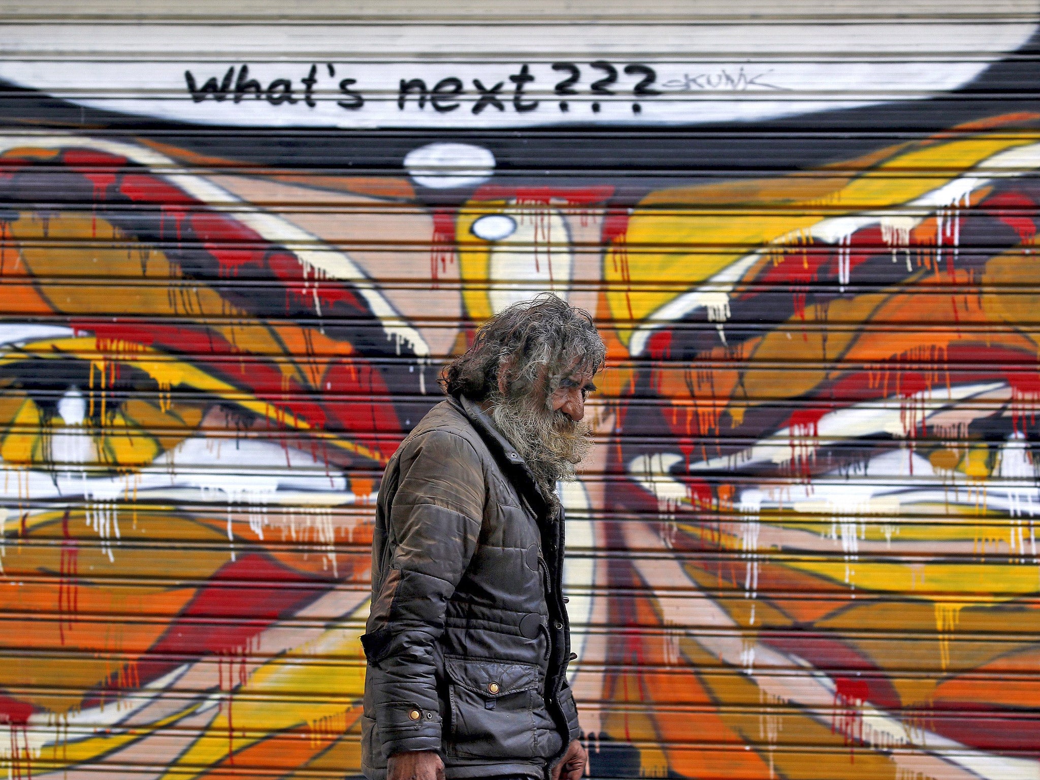 A man walks by a mural in Athens on Tuesday