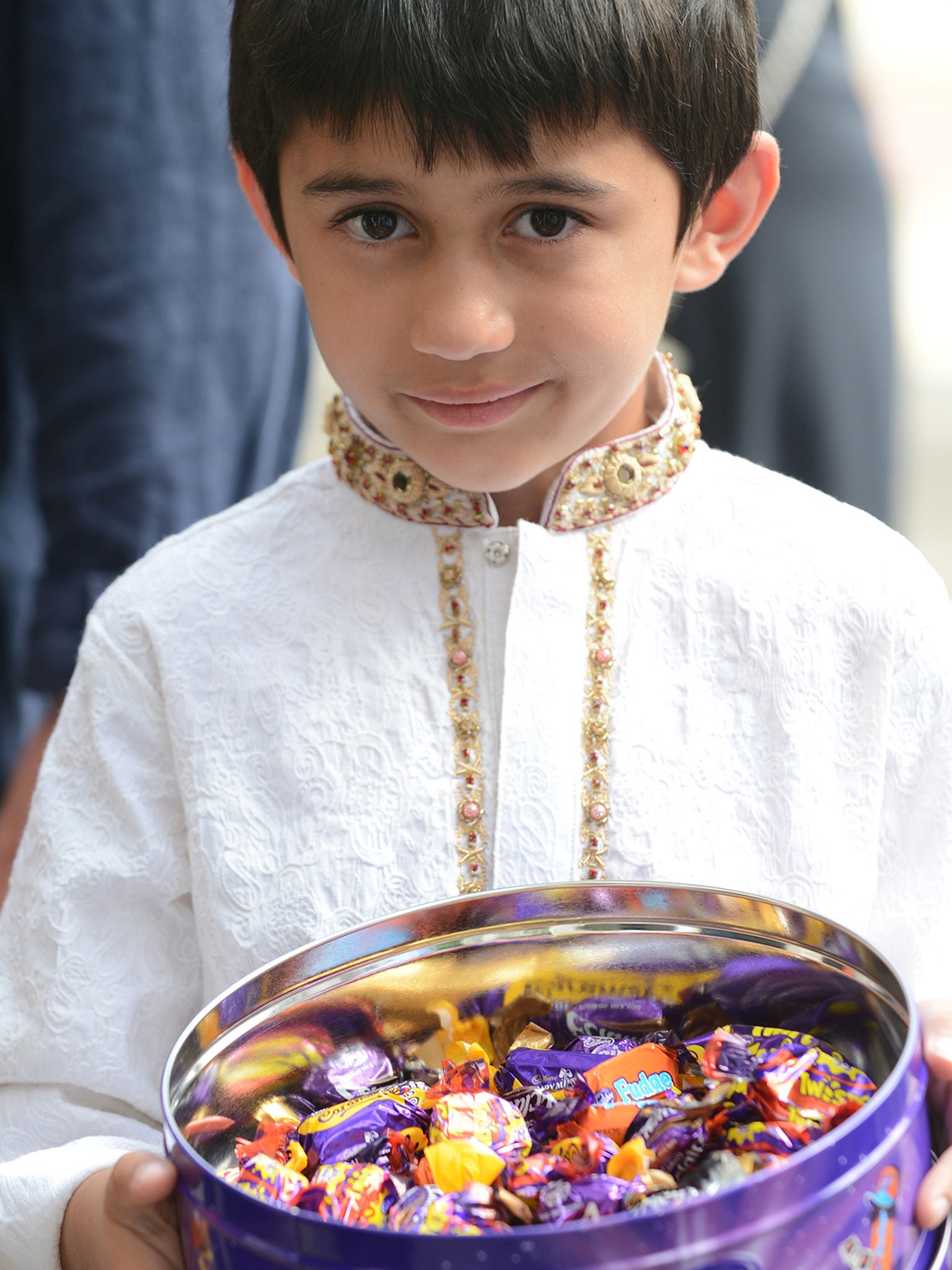A young boy holds a tin of chocolates to distribute at the Regent's Park Mosque in London after people attended prayers on Eid Al-Fitr (Image: Getty)