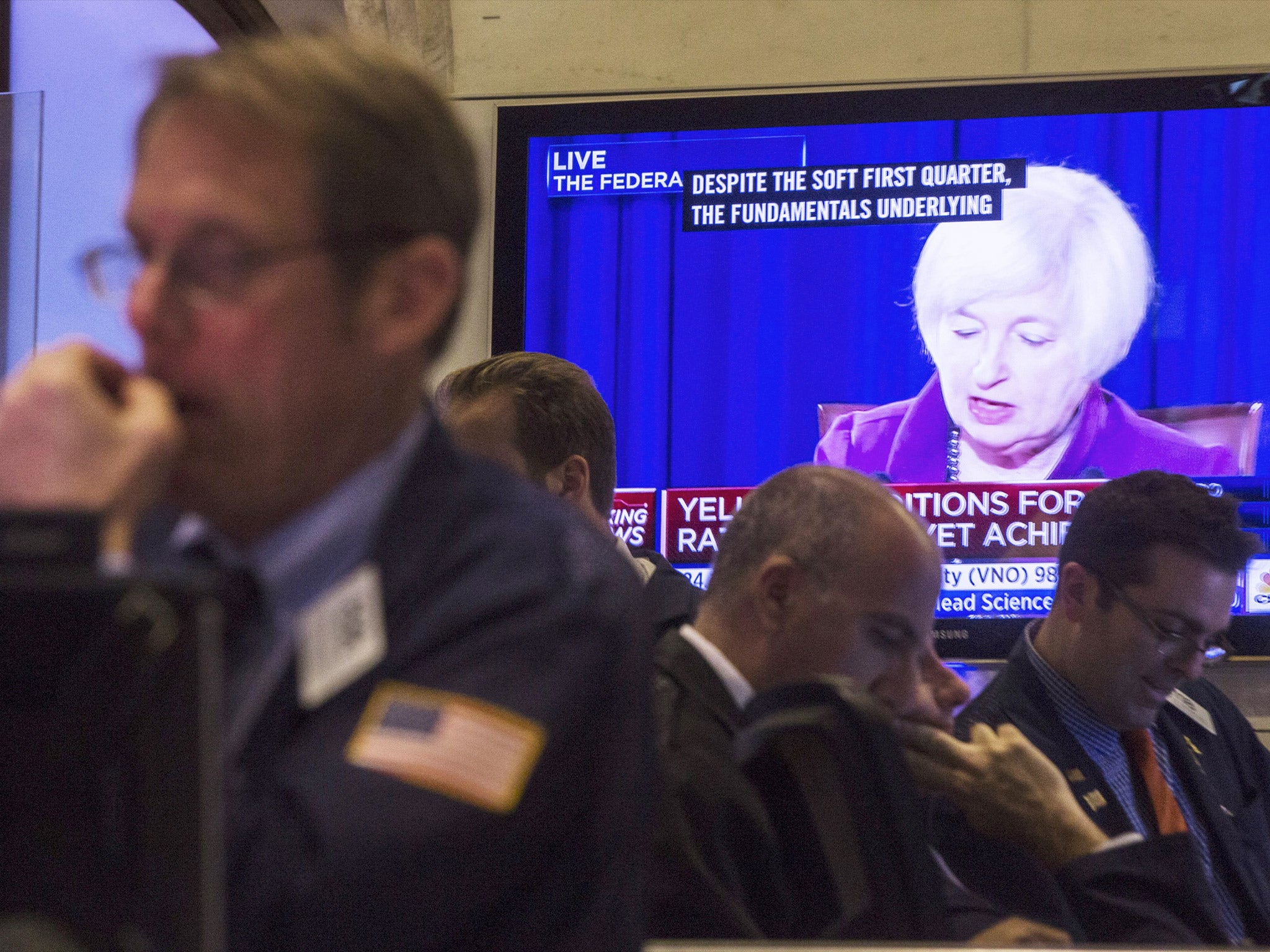 Traders in the New York Stock Exchange with Janet Yellen onscreen in the background