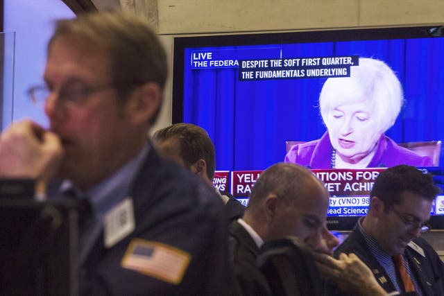 Traders in the New York Stock Exchange with Janet Yellen onscreen in the background