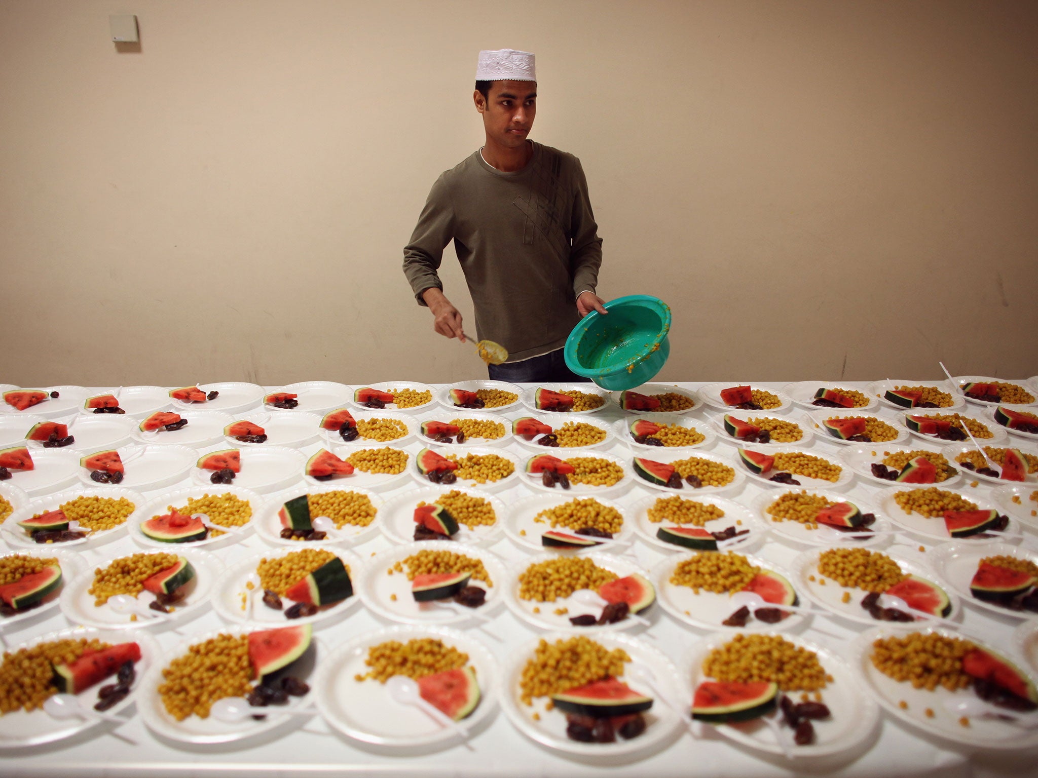 A young man serves food for Iftar, the evening meal during the Muslim holy month of Ramadan, at the London Muslim Centre (Image: Getty)