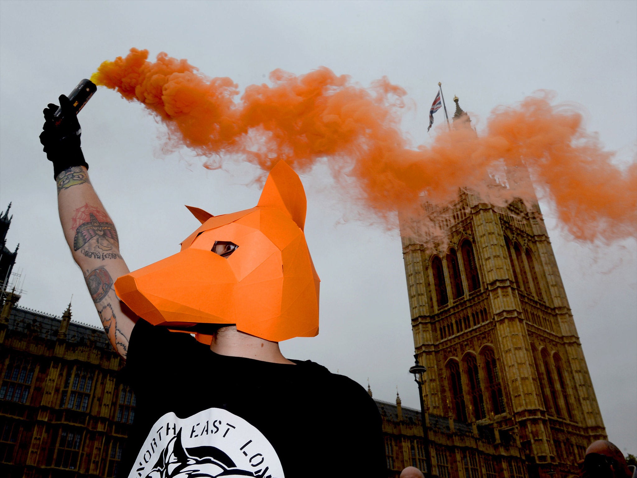 An anti-foxhunting protester lets off a flare outside the Houses of Parliament