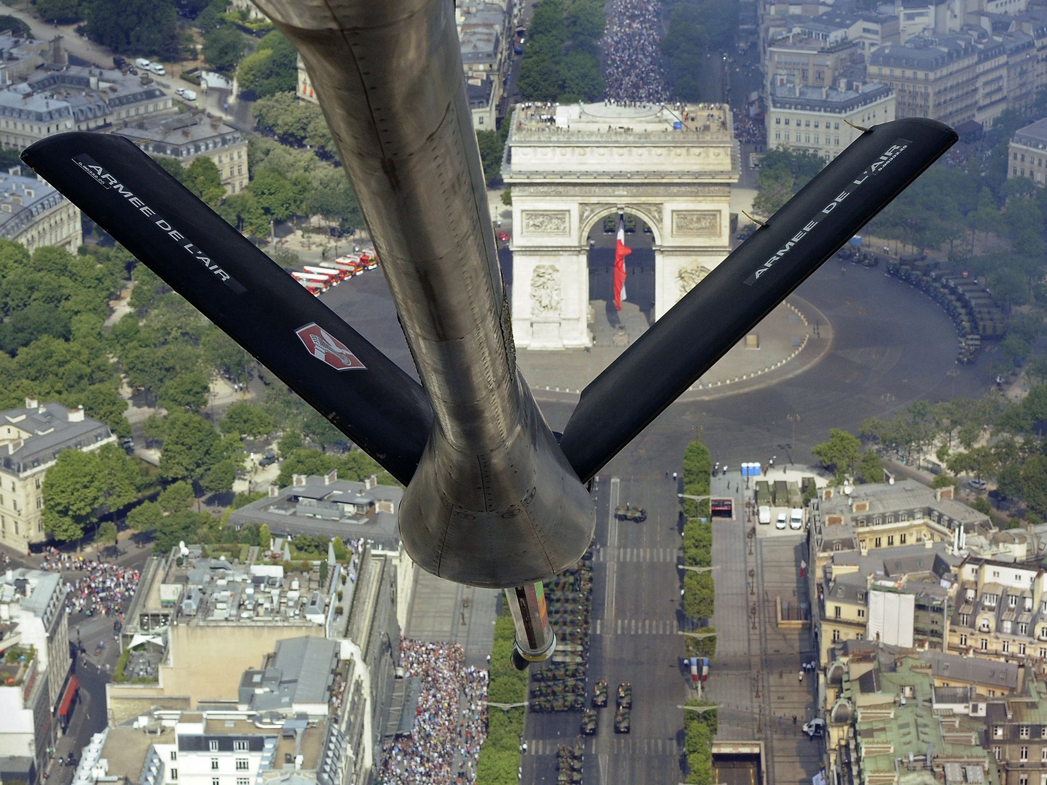 A picture taken from a French Air Force C-135 FR refueling tanker aircraft over the Arc de Triomphe monument shows troops marching on the Champs-Elysees