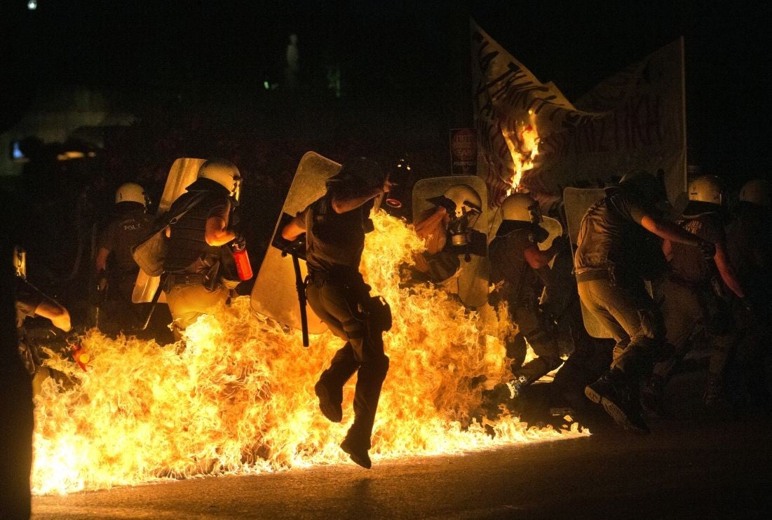 A police officer jumps to avoid fire from a petrol bomb thrown by anti-austerity protesters