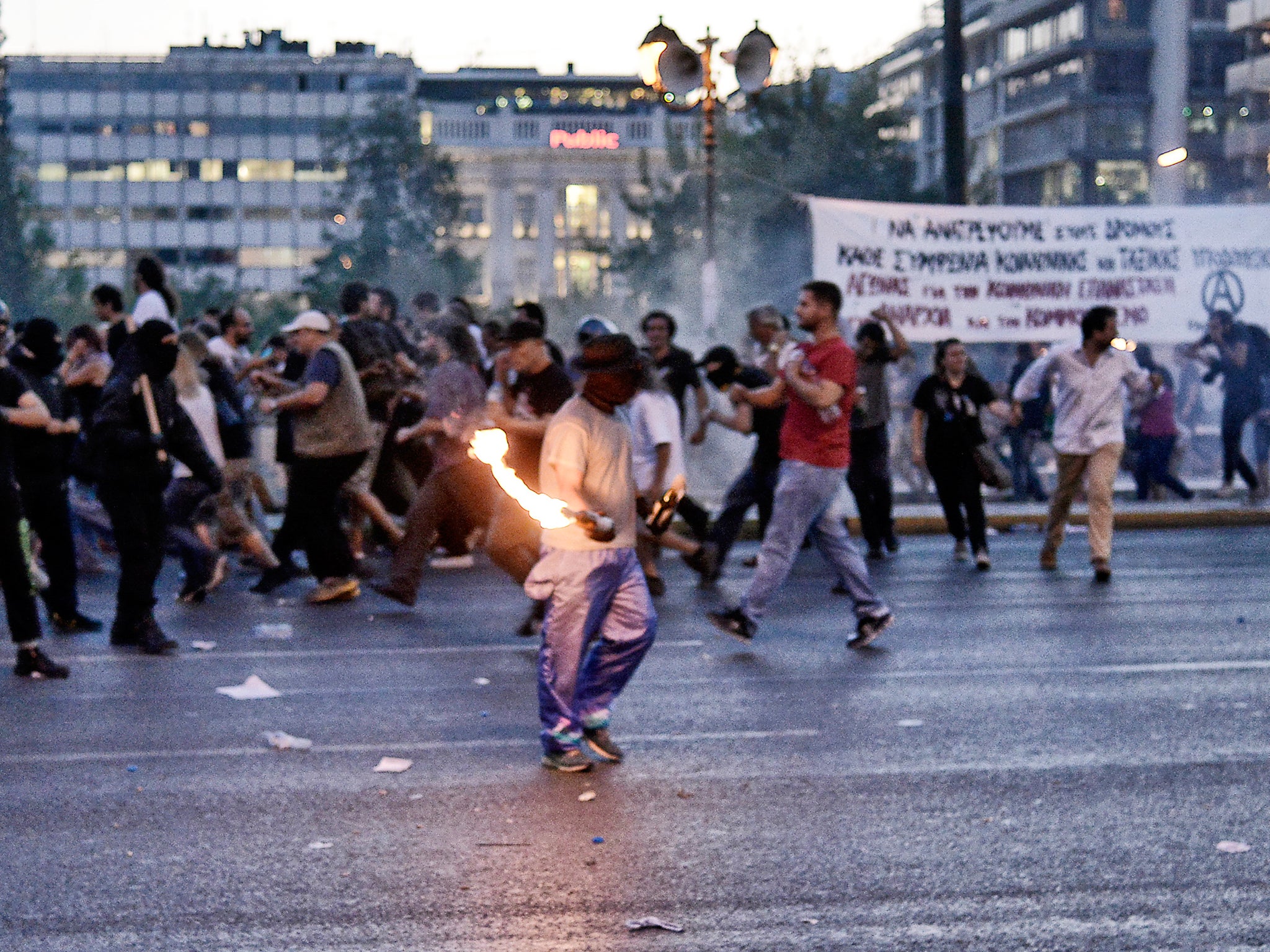 A protester clashes with riot police in front of the Greek Parliament