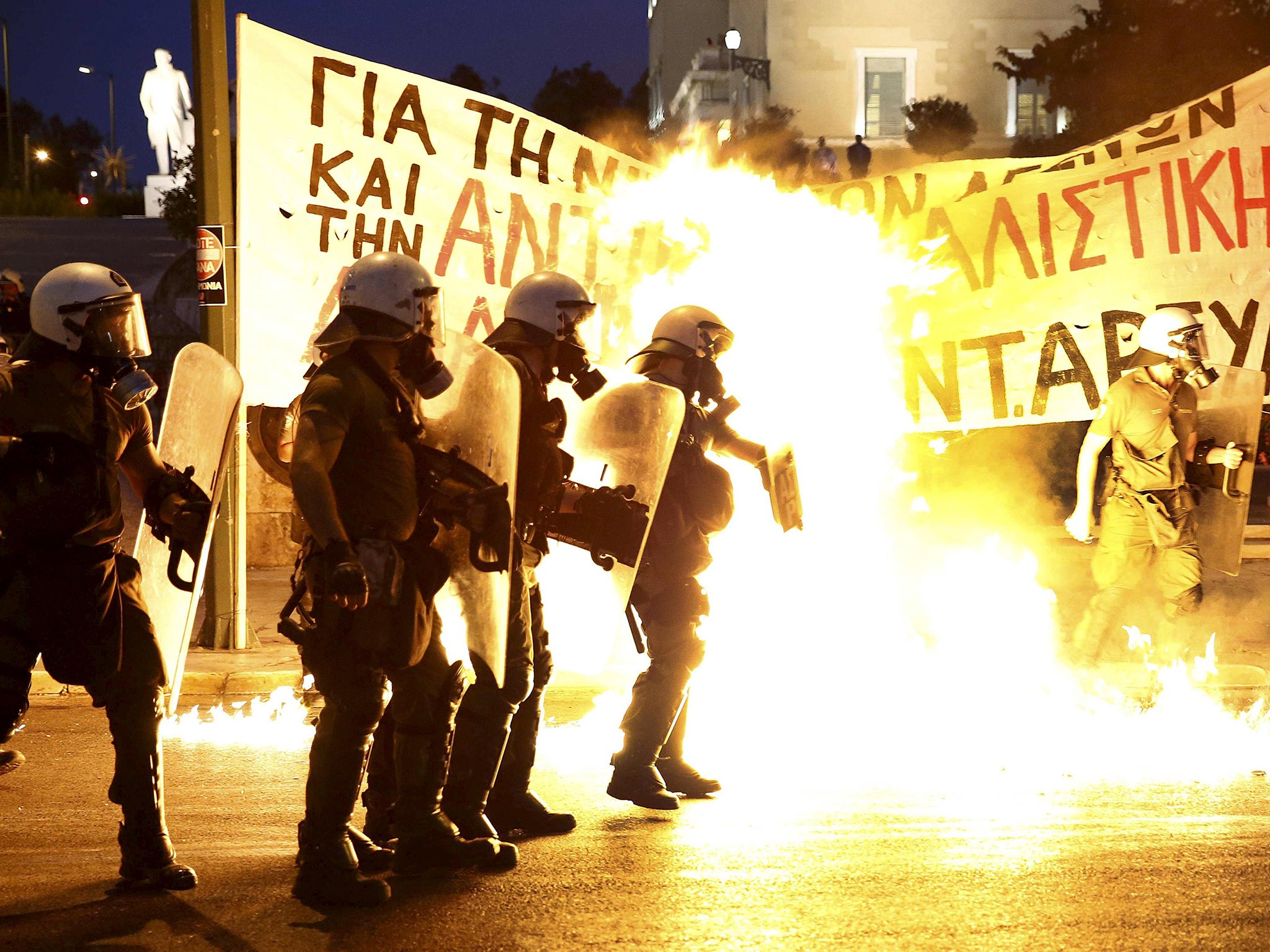 Police stand amongst the flames from exploded petrol bombs thrown by a small group of anti-establishment demonstrators