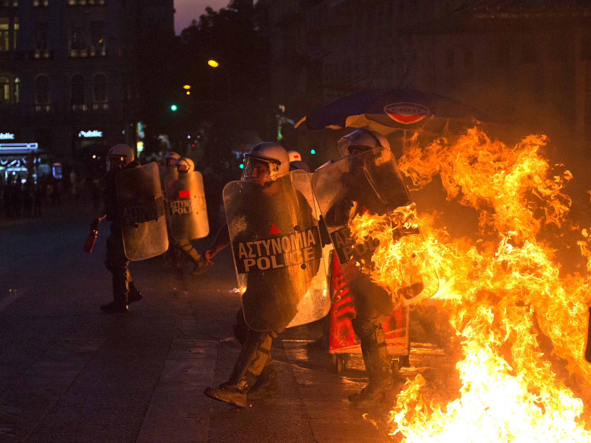 Riot police officers run away from fire as anti-austerity protesters throw petrol bombs during clashes