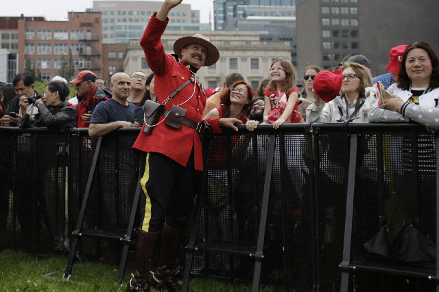 A Royal Canada Mounted Police officer takes a selfie during Canada Day festivities on Parliament Hill on 1 July, 2015