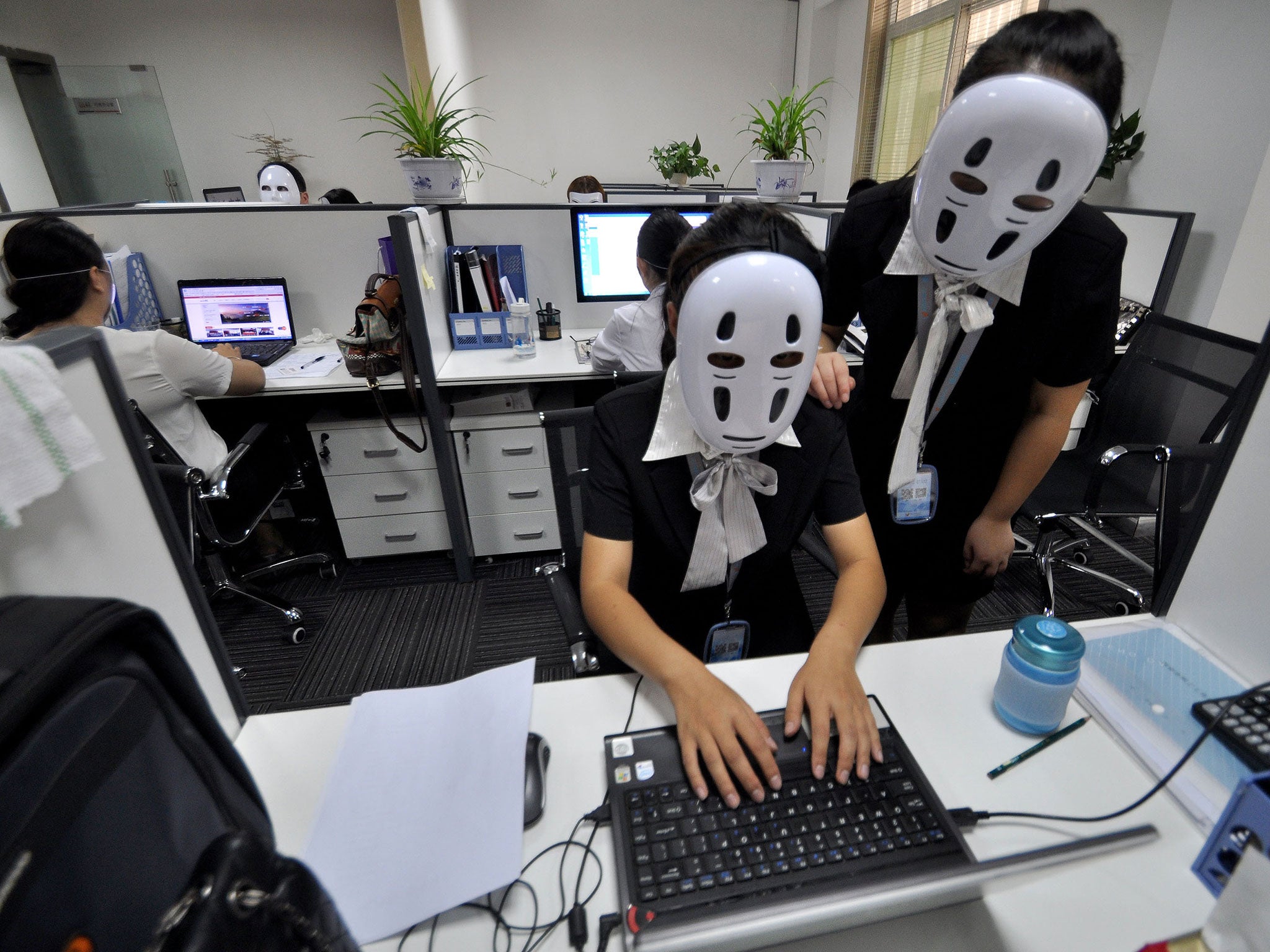 Staff wear No-Face masks during working hours at a service company on July 14, 2015 in Handan, Hebei Province of China. As a service company, its staffs must smile to customers everyday. On 'No-Face Day', the staffs wore No-Face masks to reduce pressure and relax themselves. No-Face is a silent masked creature who has no facial expressions in Japanese animated fantasy film 'Spirited Away'.