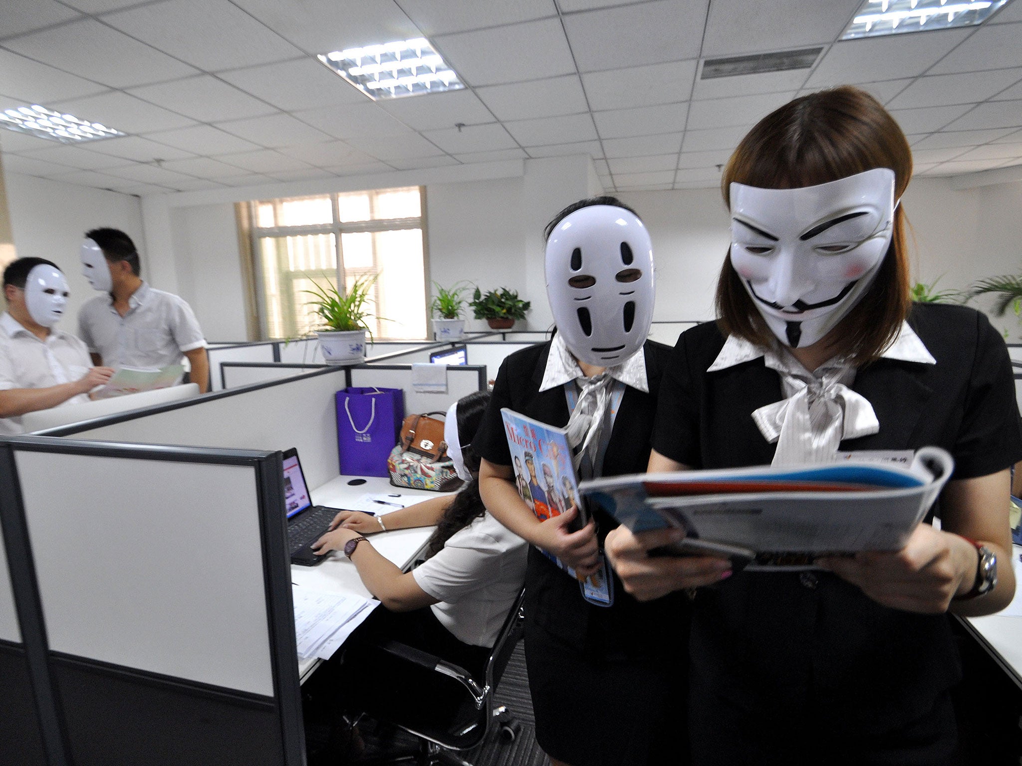 Staff wear No-Face masks during working hours at a service company on July 14, 2015 in Handan, Hebei Province of China. As a service company, its staffs must smile to customers everyday. On 'No-Face Day', the staffs wore No-Face masks to reduce pressure a