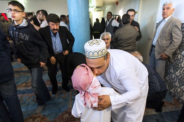 A father kisses his son after taking part in Eid-ul-Fitr prayers at the Mevlavana Mosque in Rotterdam in Netherlands this morning