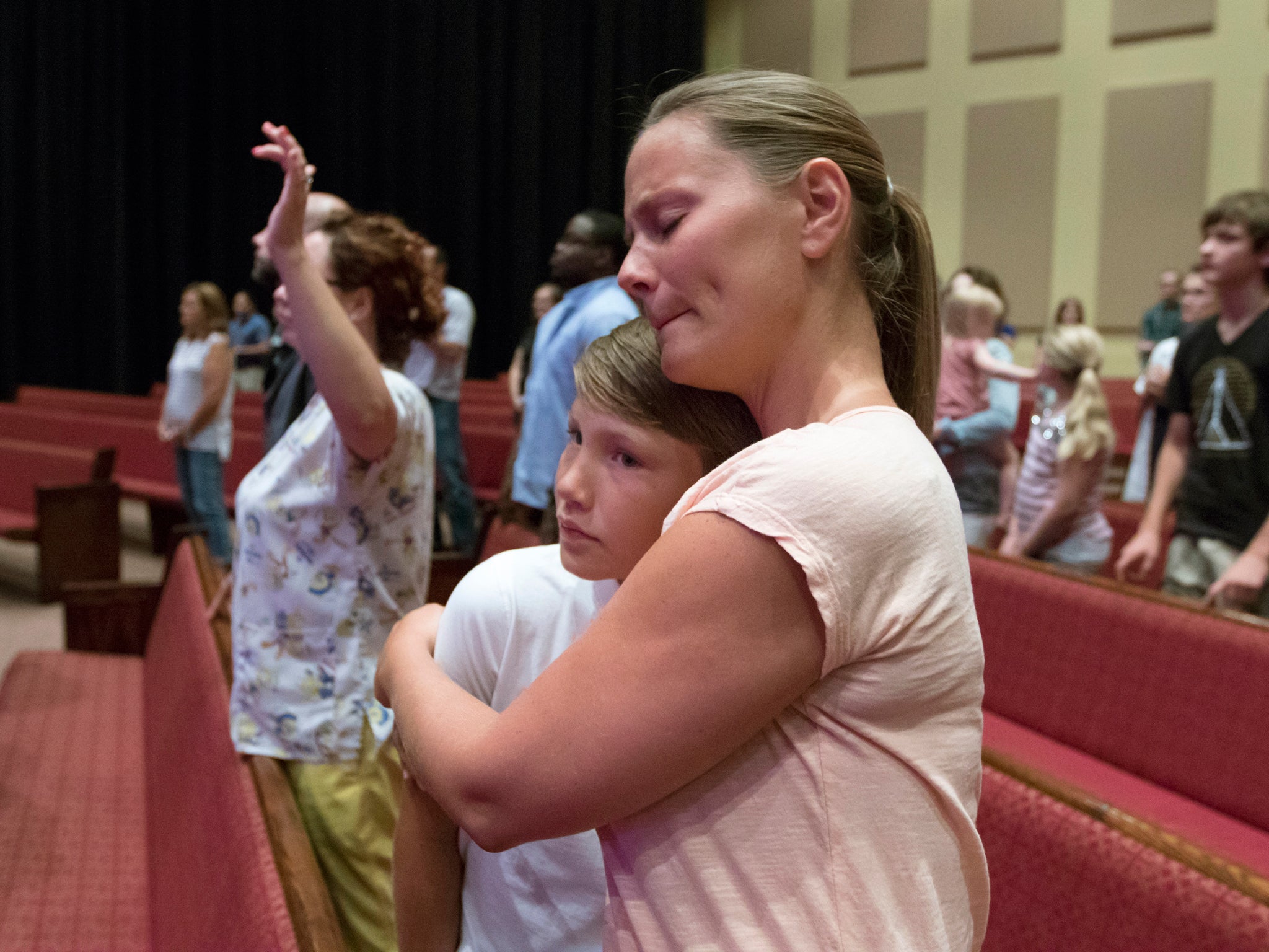 Melody Kelley, front right, hugs Logan Wallace during a prayer vigil at Redemption Point Church for the victims of the shootings