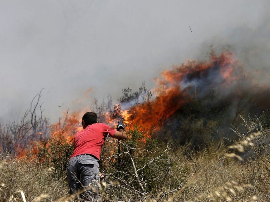 v=A man tries to extinguish flames on a mountain in Athens