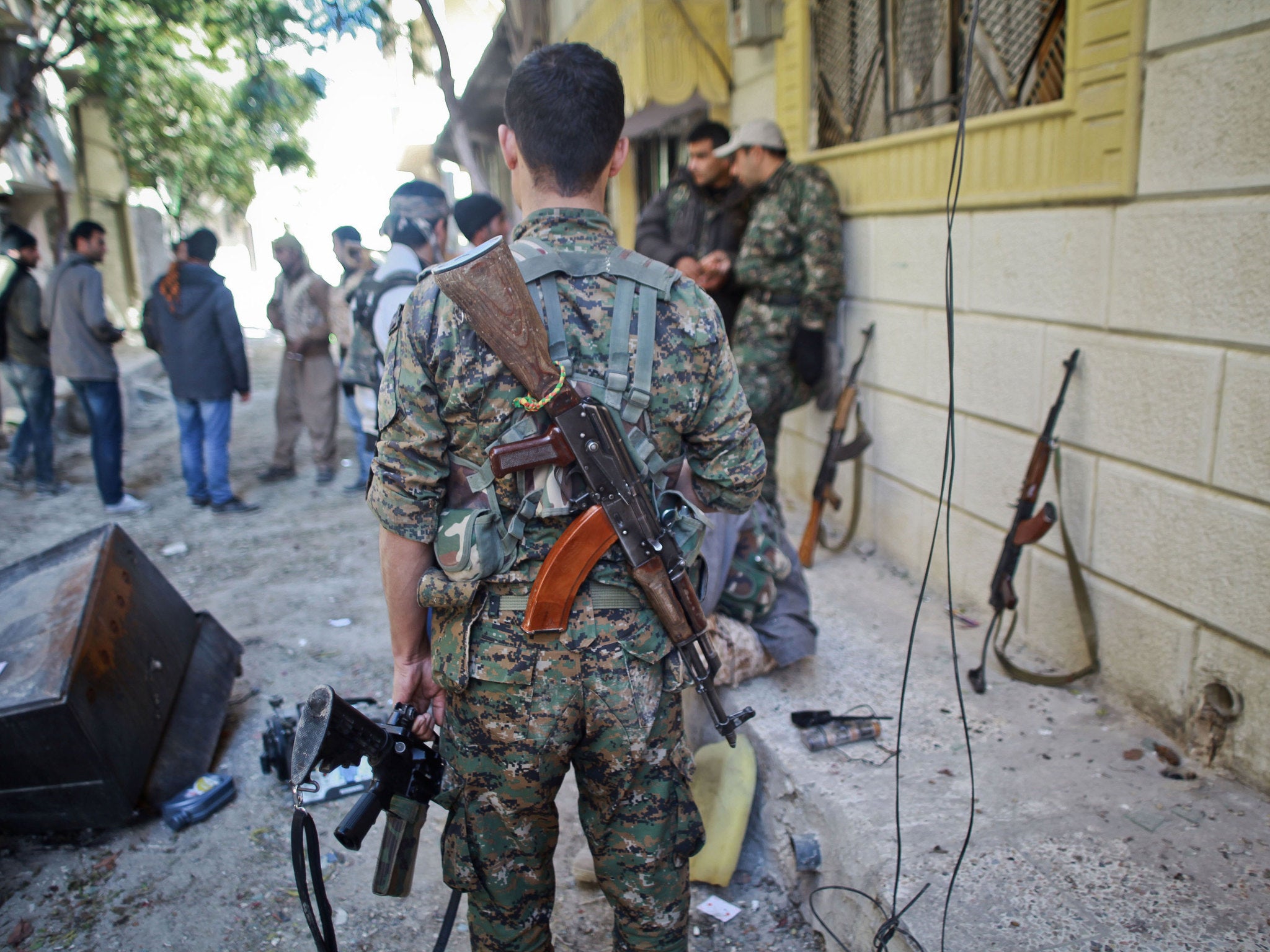 Armed fighters of the Syrian Kurdish People's Protection Units gather on a street before fighting against Isis