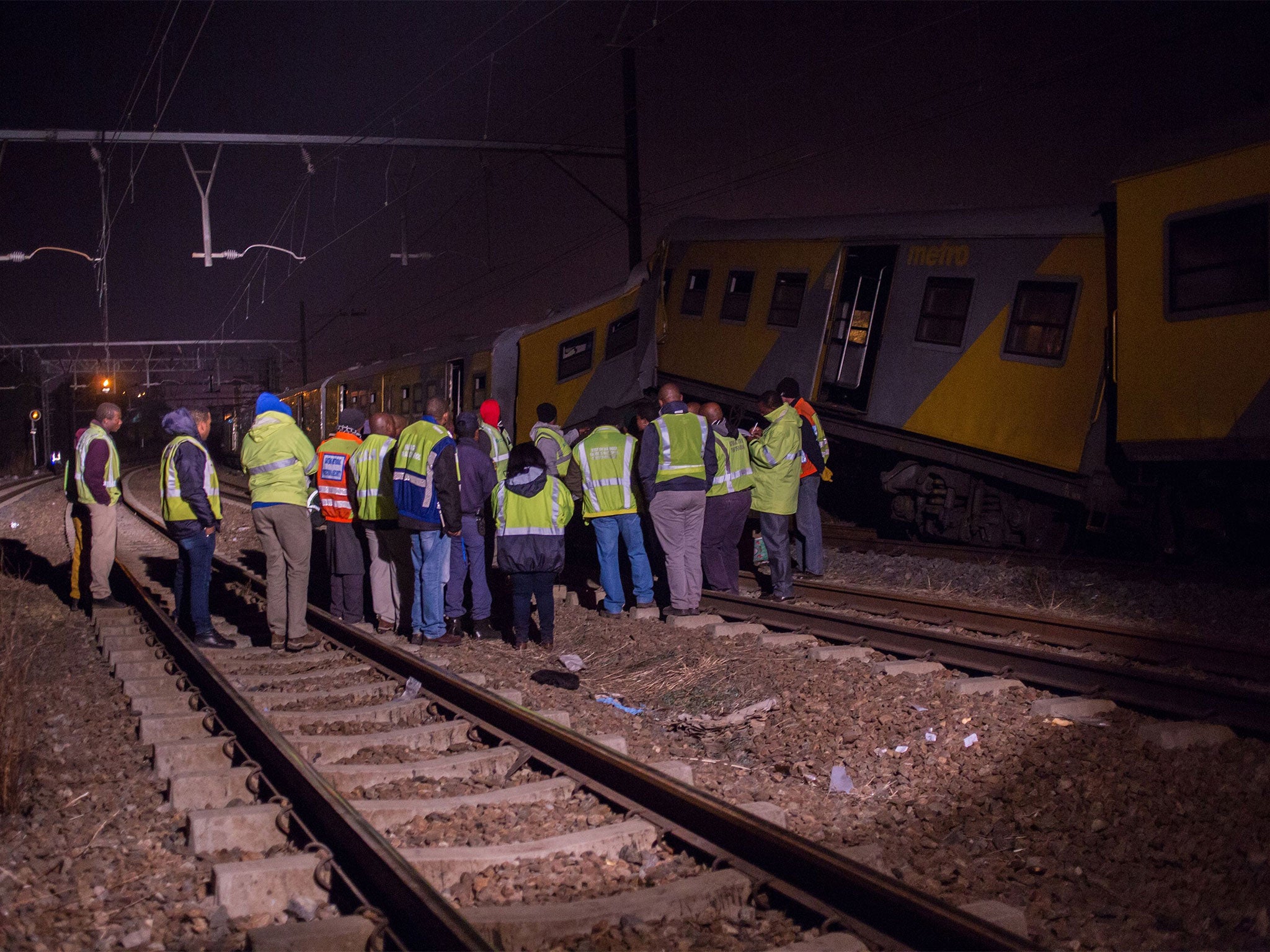 Railway inspectors and emergency personnel stand near the site of the crash