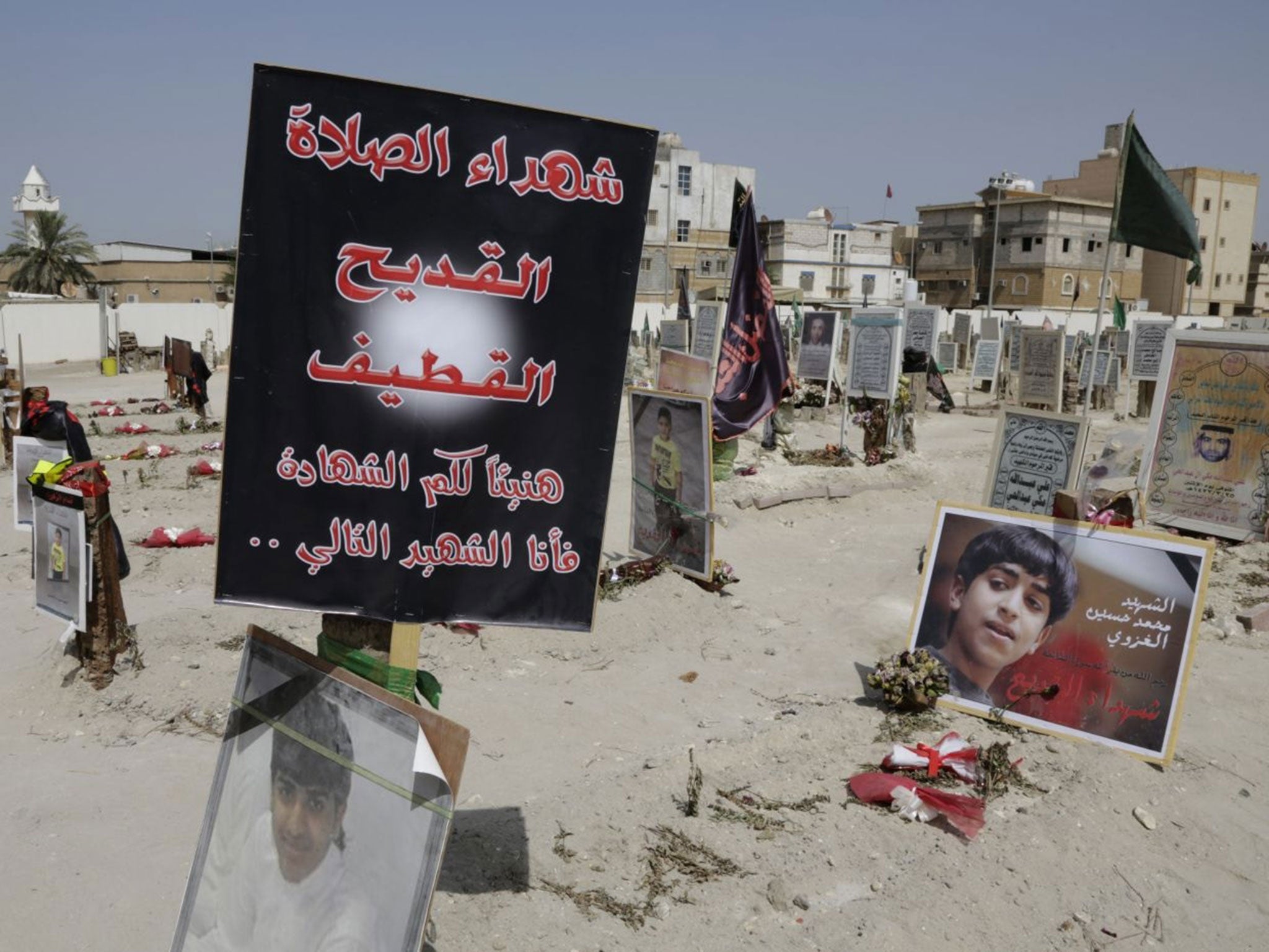 Religious flags, photographs and tributes to 21 victims of a suicide bombing of a Shiite mosque, at a cemetery in al-Qudeeh, Saudi Arabia.