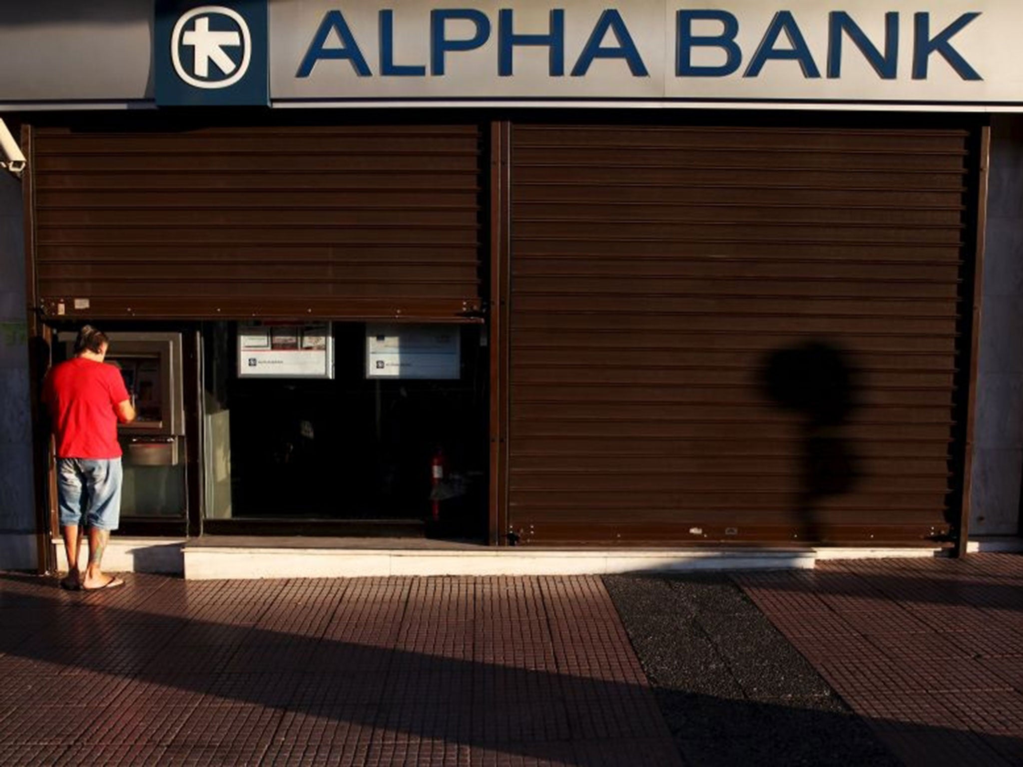 A man withdraws money at an Alpha Bank branch ATM in central Athens, Greece, July 19, 2015. The Greek government ordered banks to open on Monday, three weeks after they were shut down to prevent the system collapsing under a flood of withdrawals, as Prime