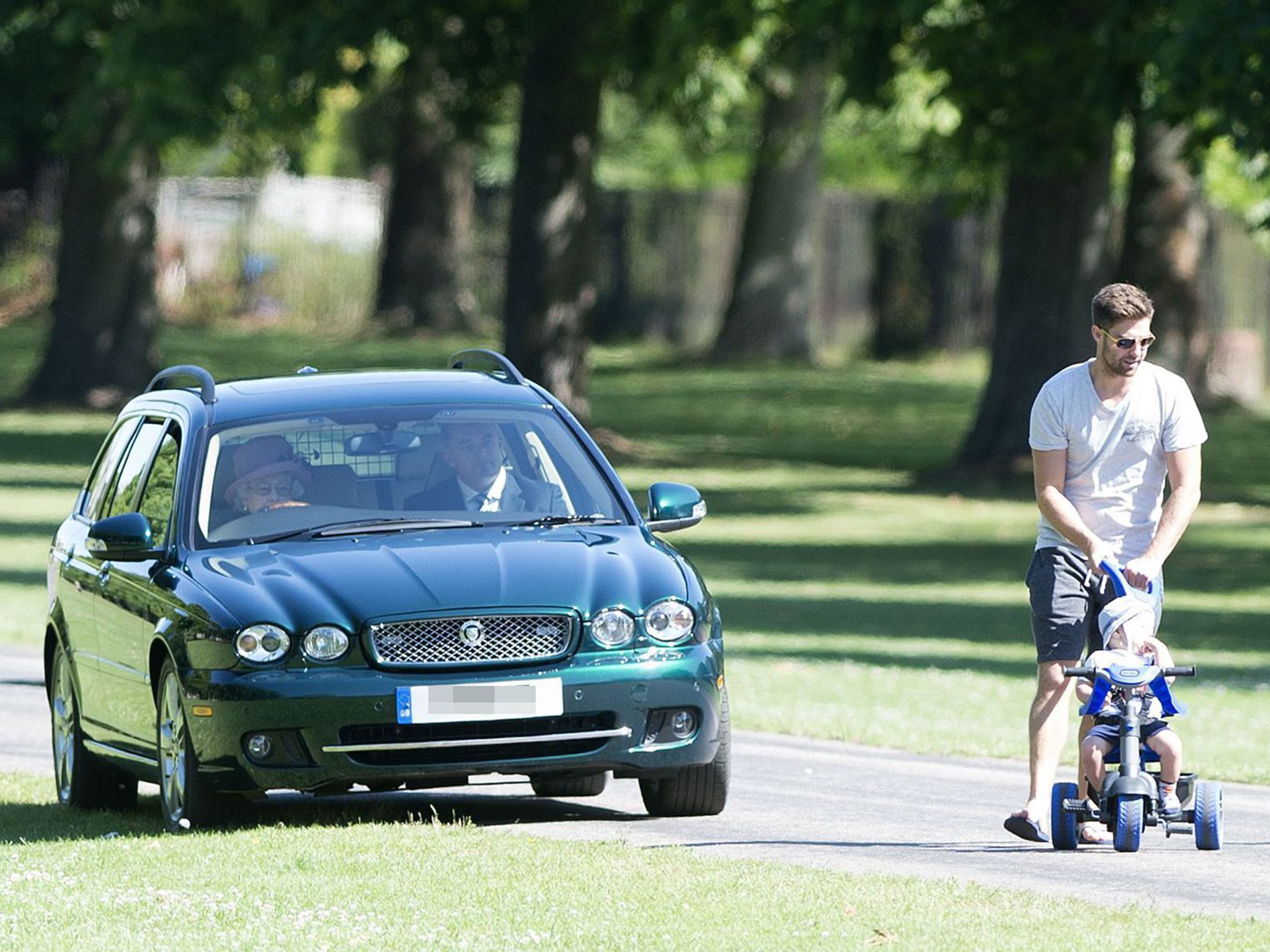 Queen Elizabeth driving on the long walk, steers on to the grass to avoid Scarlett Vincent, Toby Core and their son Teddy in Windsor Great Park