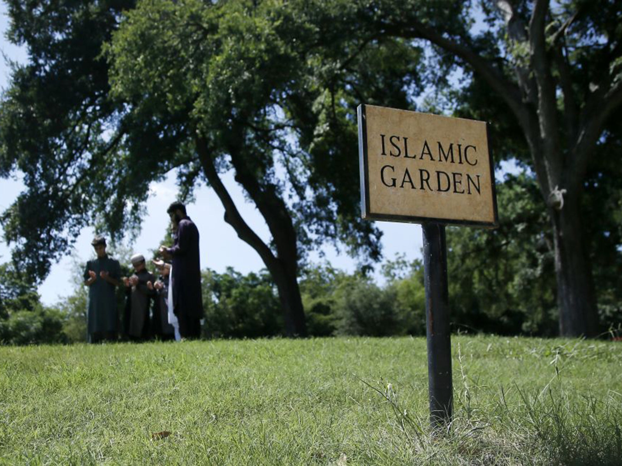 A family gathers in prayer as they visit a family member buried in the Islamic Garden at Restland Cemetery in Dallas