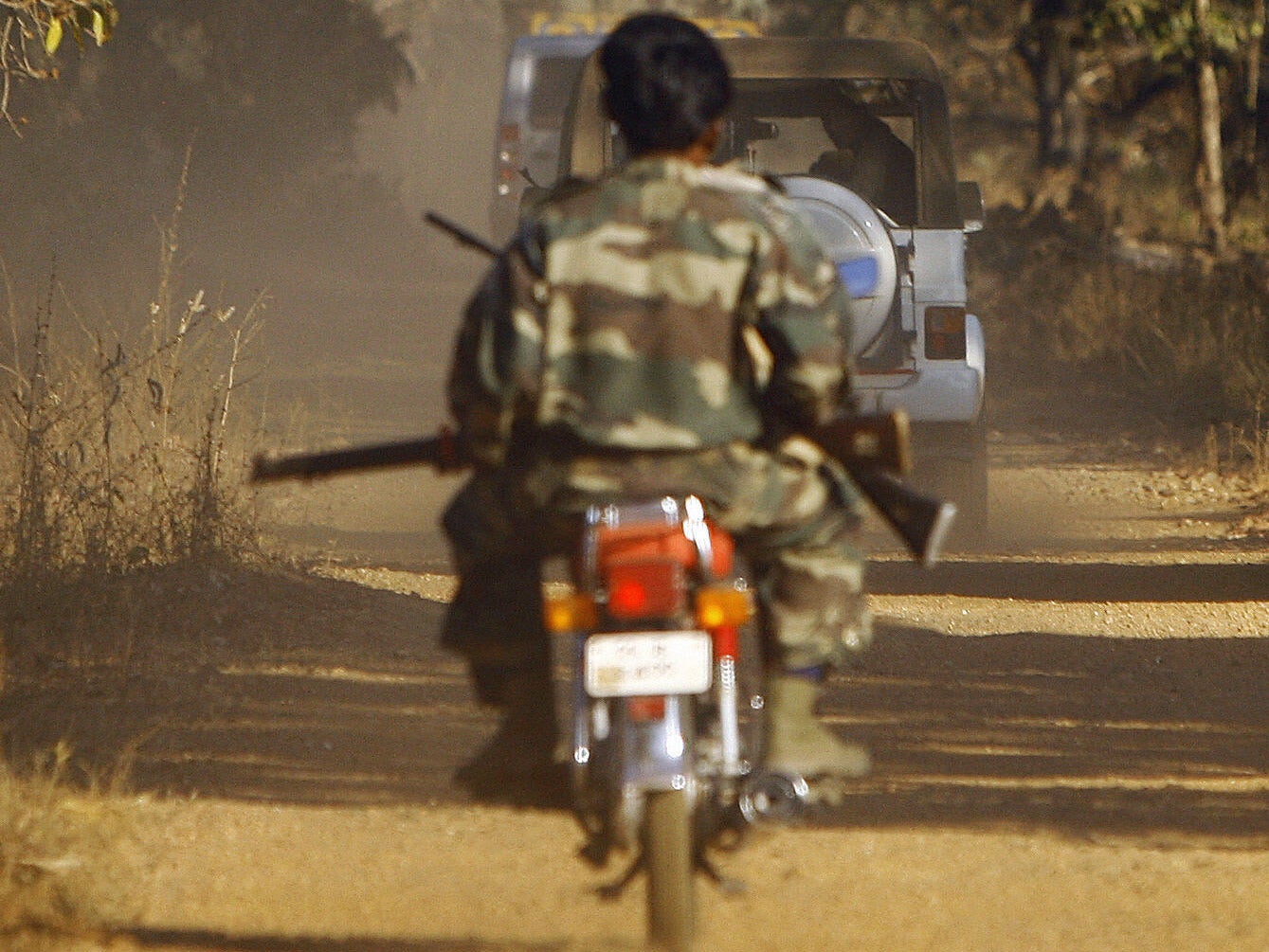 A jeep carrying villagers waits for a convoy comprised of paramilitary forces and Special Police Officers