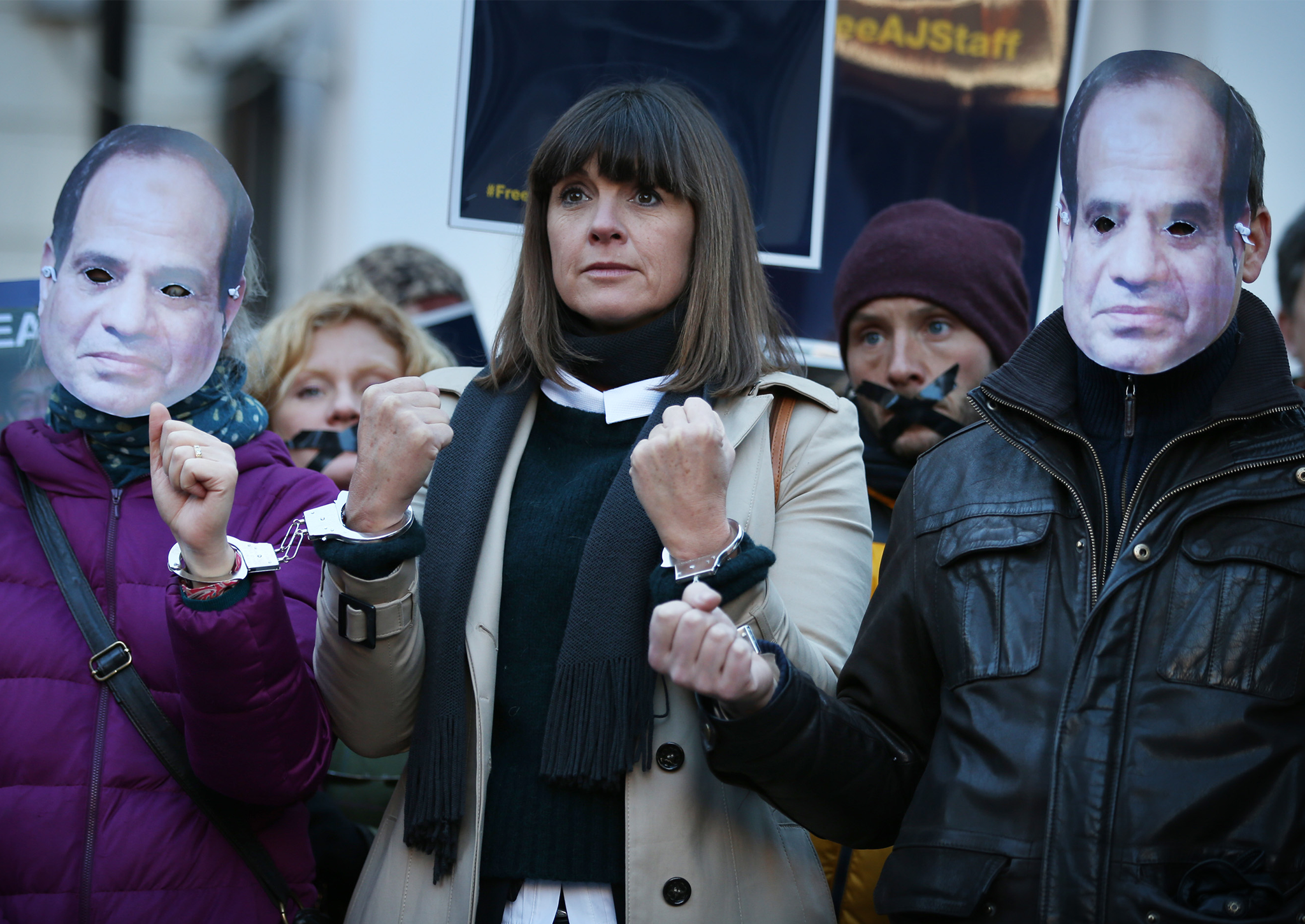 Sue Turton stands handcuffed to fellow supporters, wearing masks depicting President el-Sisi, as they demonstrate in support of jailed colleagues outside the Egyptian embassy last year