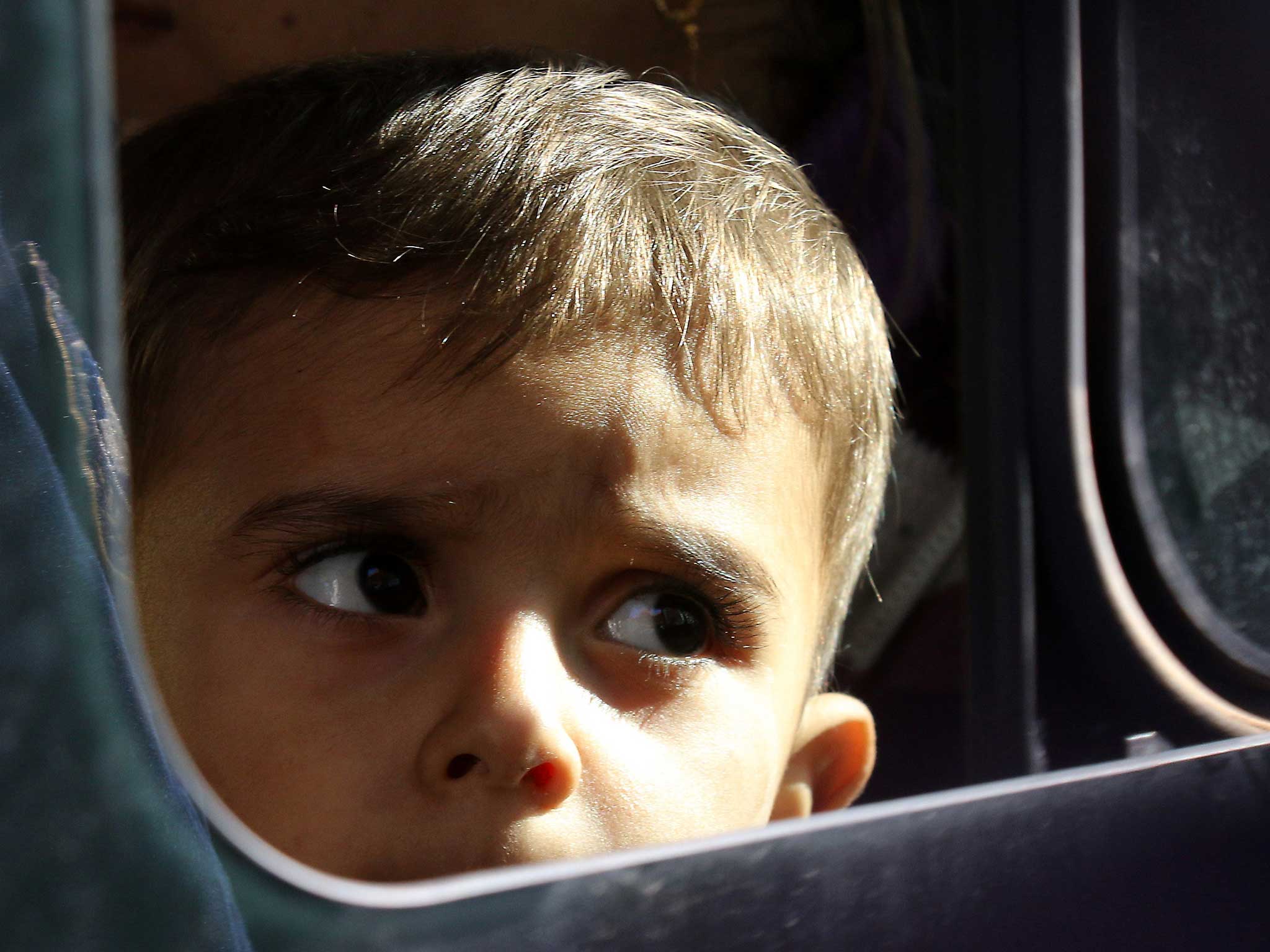A child looks out from a bus as he arrives in Greece: Migrant children are often supported by charities such as Smile for the Child