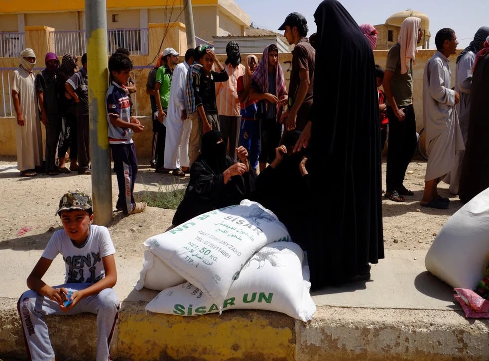 Families in Haditha receive sacks of flour in a food aid delivery July 16. Prices of food and gasoline have skyrocketed in the town after supply routes were cut off