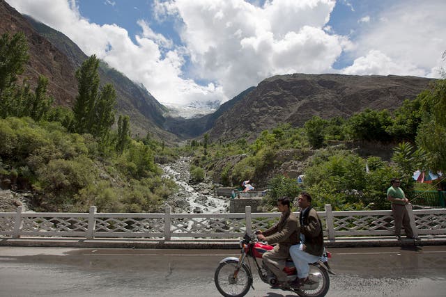 Men ride past on the Karakoram Highway at a viewpoint of the Rakaposhi Peak in the Karakoram mountain range in Pakistan