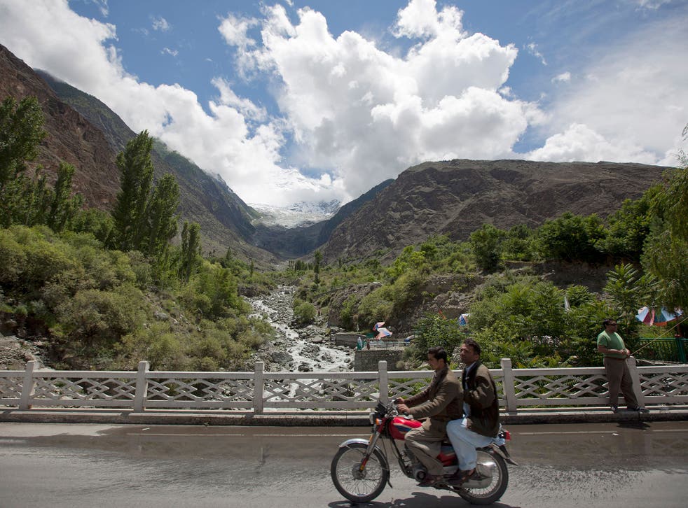 Men ride past on the Karakoram Highway at a viewpoint of the Rakaposhi Peak in the Karakoram mountain range in Pakistan