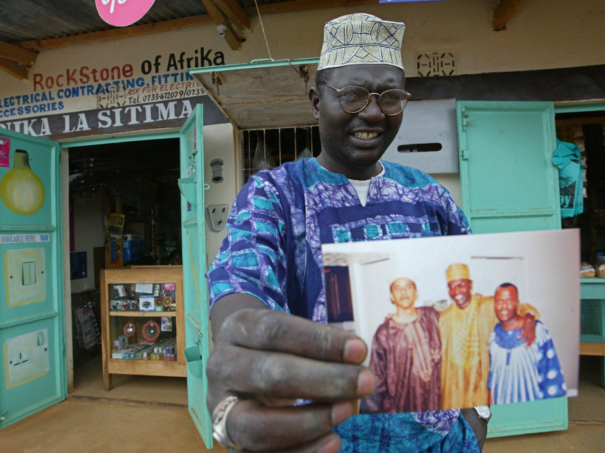 Malik Obama the older brother of Barack Obama holds an undated picture of Barak, left and himself, middle outside his shop in Siaya in eastern Kenya