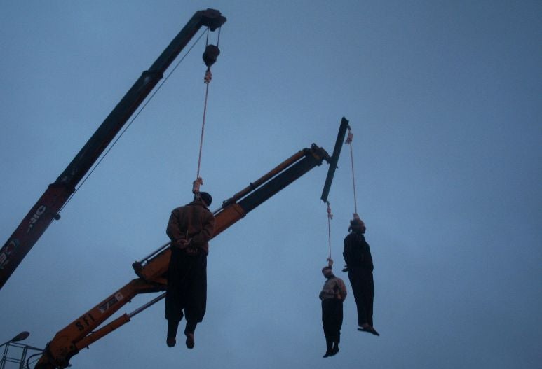Three Iranian drug traffickers hang limply from the nooses as it snows in a square in the central city of Qom